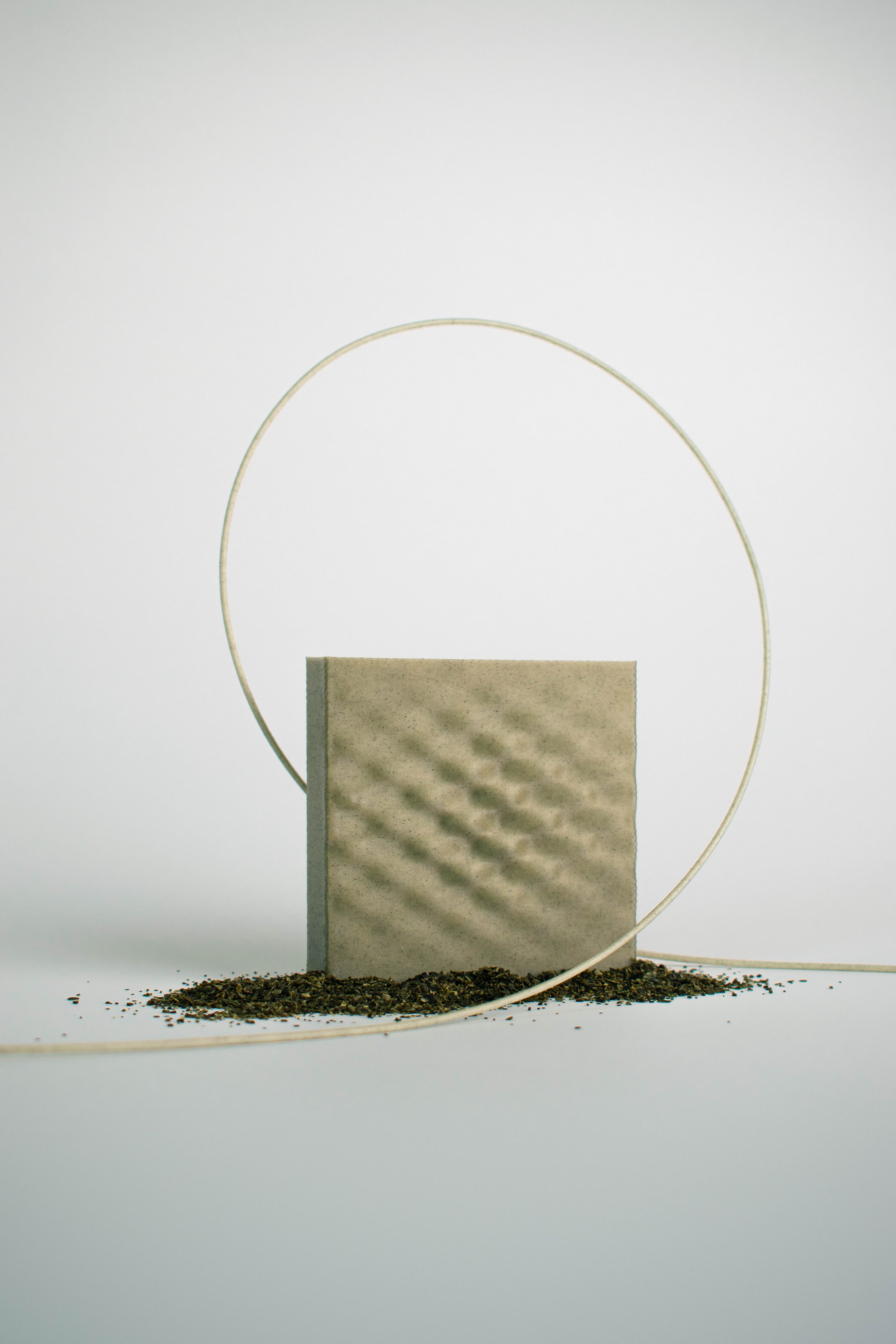 Seaweed Green 3D-printed surface sample encircled by filament above seaweed residue