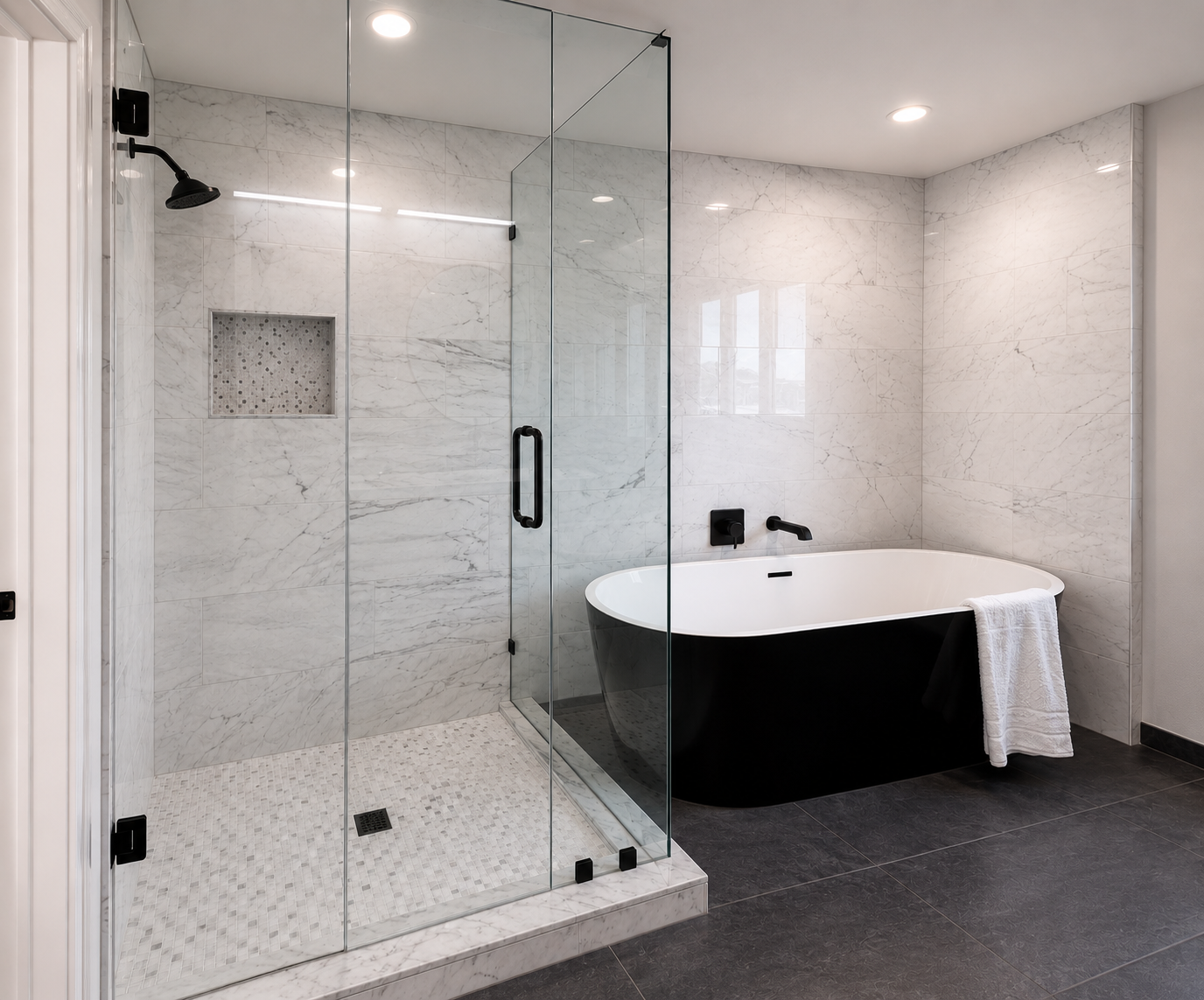 Black freestanding tub sits elegantly behind this 90° steam shower enclosure. The large format marble tile wall and Matte black hardware flows smothly between glass and tub.