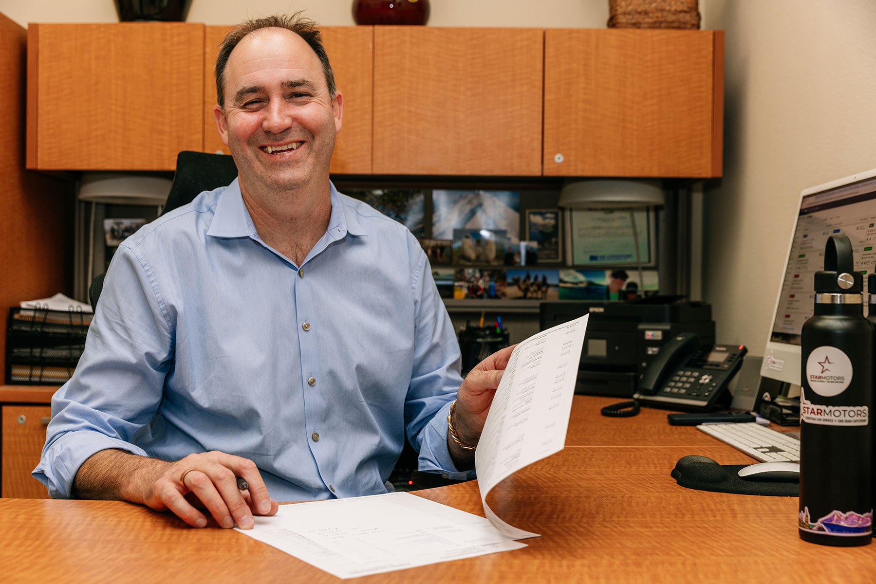 Chris Knuth smiling at his desk, flipping through paperwork