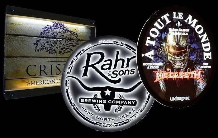 Photograph of three illuminated signs on a dark wall. The signs display logos and names of brewing companies and a music event, including Rohr & Sons Brewing Company, TOUT LE MONDE with Megadeth, and a sign for CRISP American Grill.