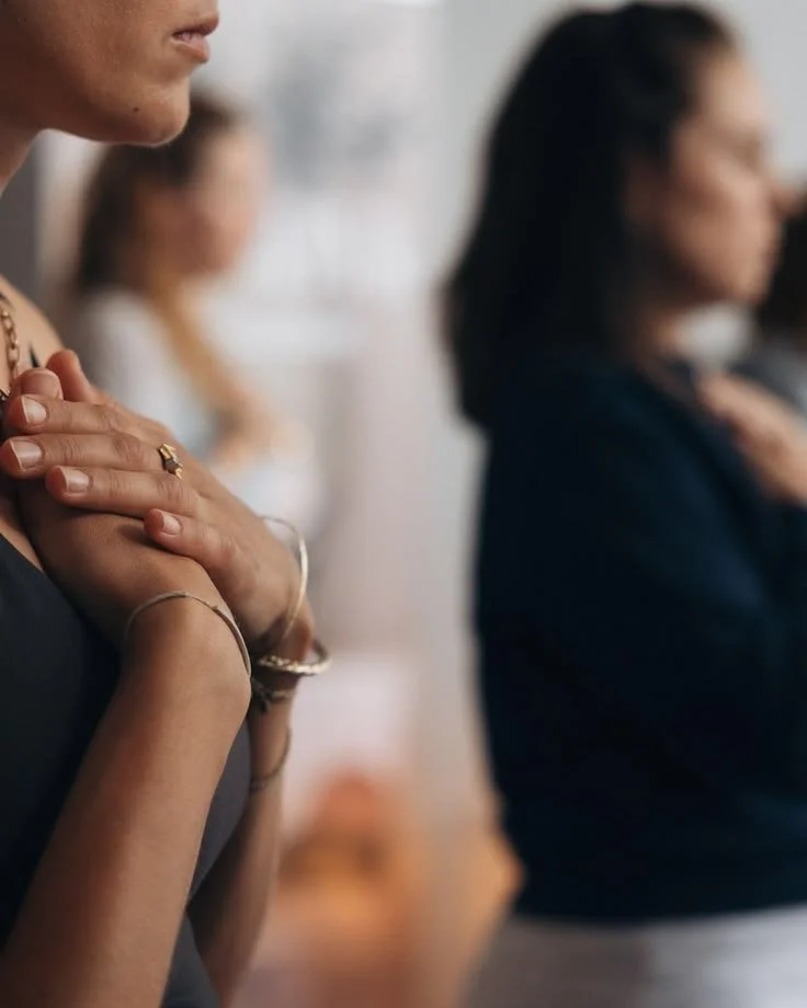Close-up of two women with their hands over their hearts, participating in a moment of intentional connection.