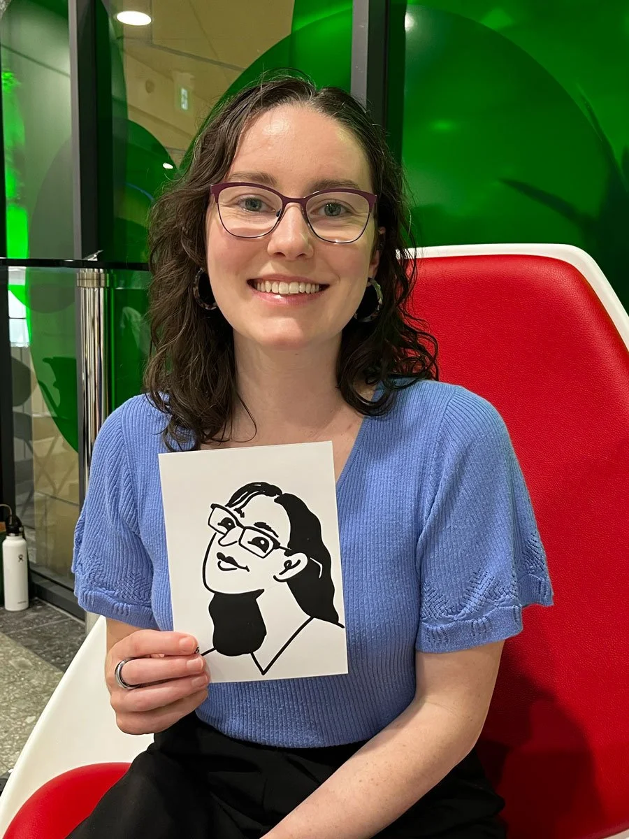 Social west guest in a blue top and glasses holding her derpy portrait. 