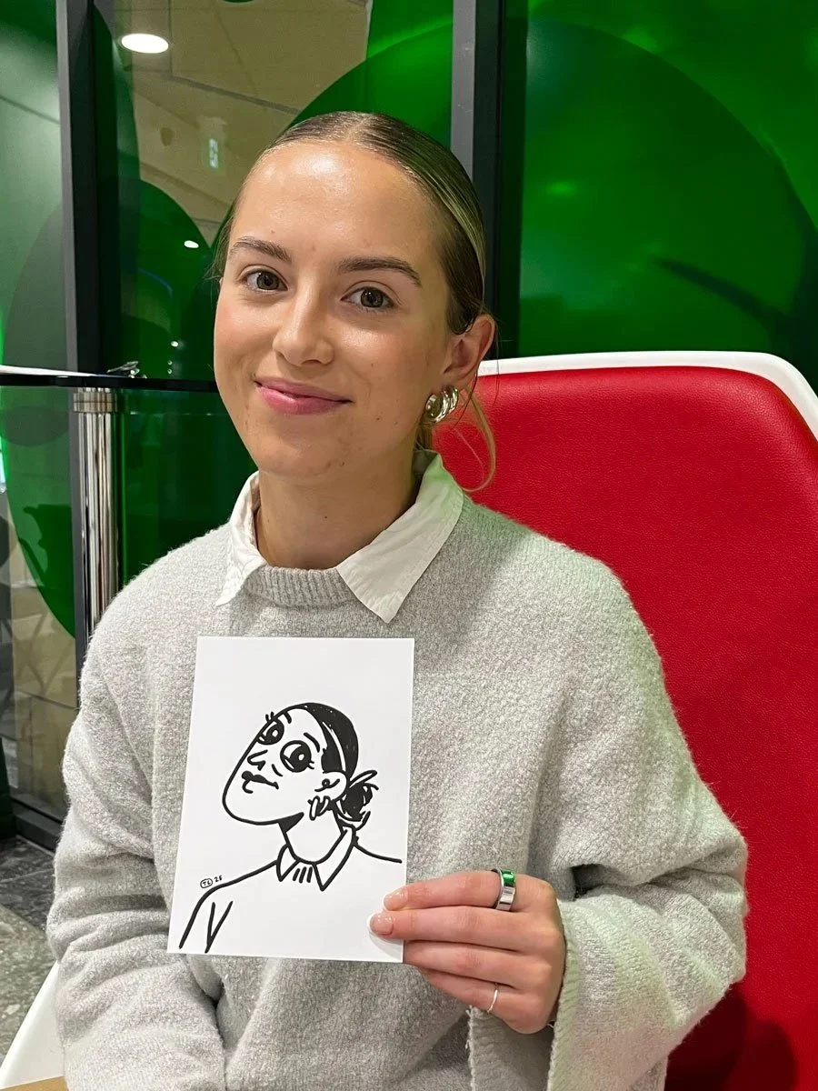 A woman in a grey sweater with a colar coming out the top, with tied back hair and large earings holding her derpy portrait