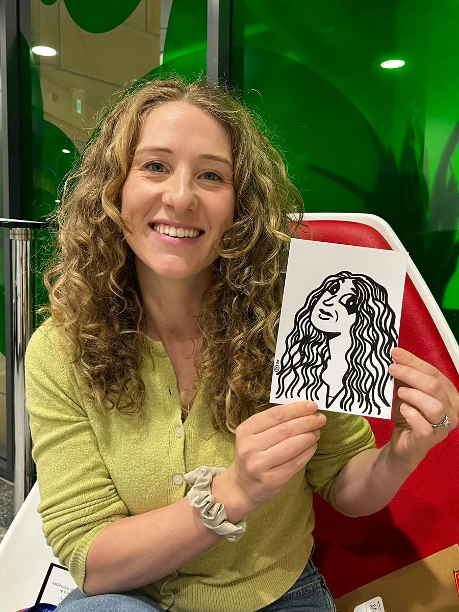 woman in a green top and thick curly hair holding up a derpy portrait which features mostly hair