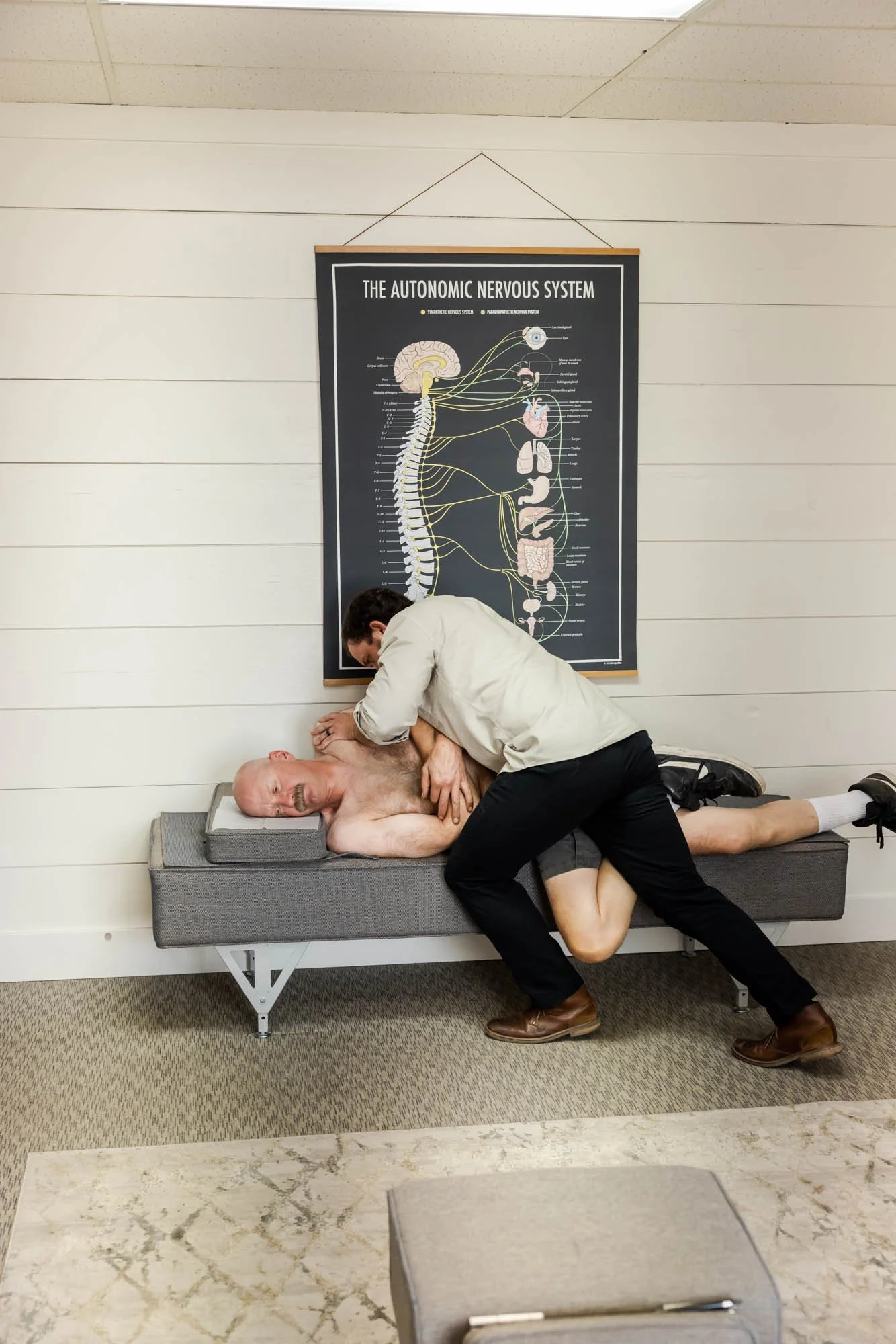 Dr. Peter Fennelly of Two Sparrows Chiropractic in Whitefish, MT is performing a Gonstead adjustment on a male patient using the pelvic bench,