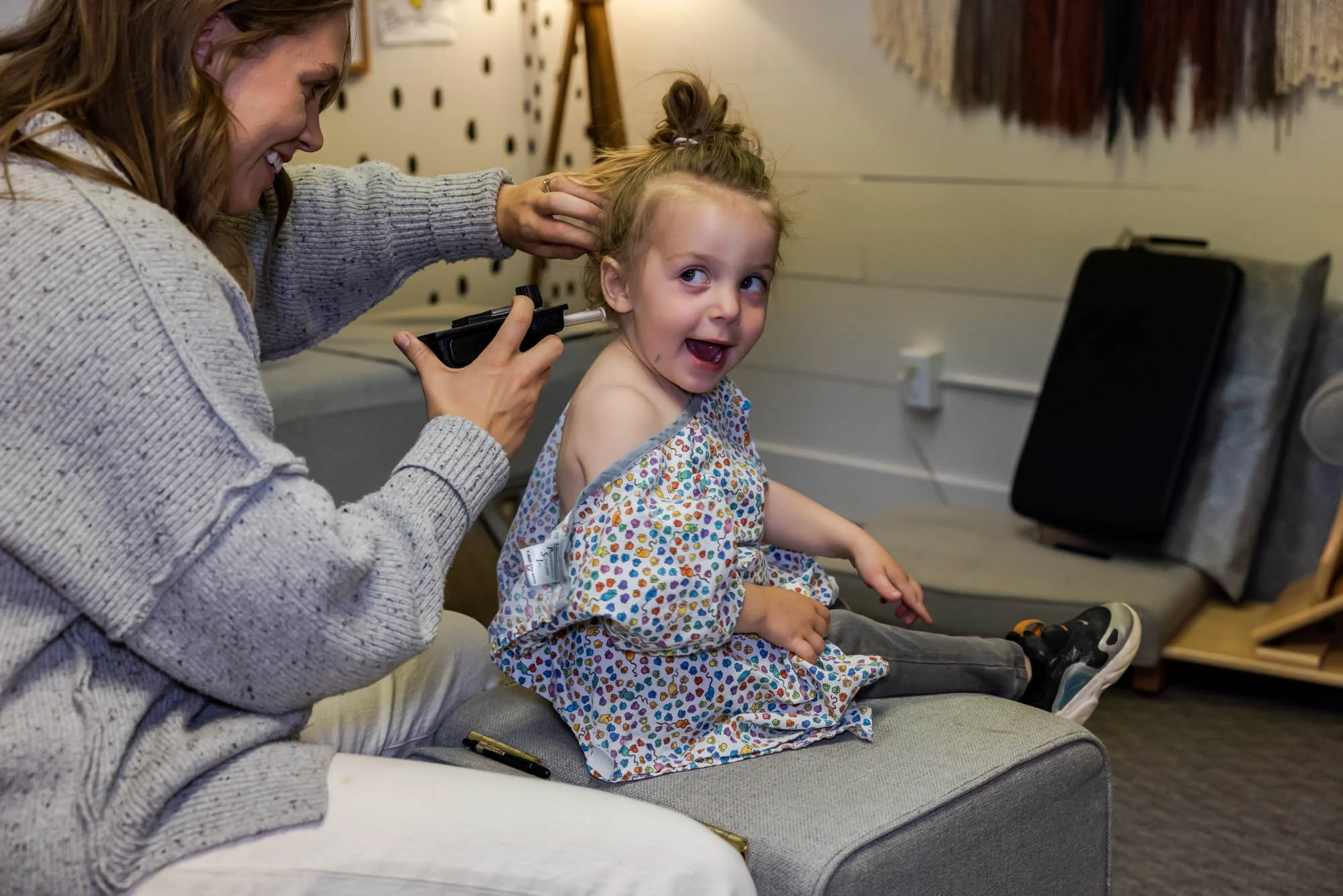 Dr. Jordan Fennelly of Two Sparrows Family Chiropractic in Whitefish, Montana in her office with a female pediatric patient, performing a Gonstead spinal check using a temperature differential divide to find heat changes in the patient's spine.