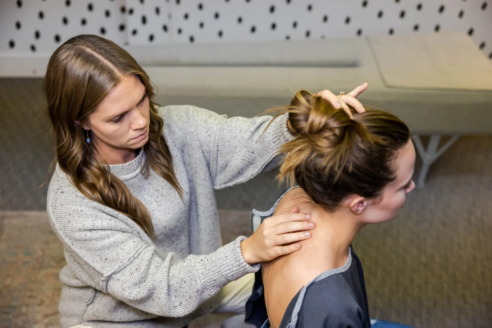 Dr. Jordan Fennelly of Two Sparrows Chiropractic in Whitefish, MT is assessing the cervical spine of a young female patient.