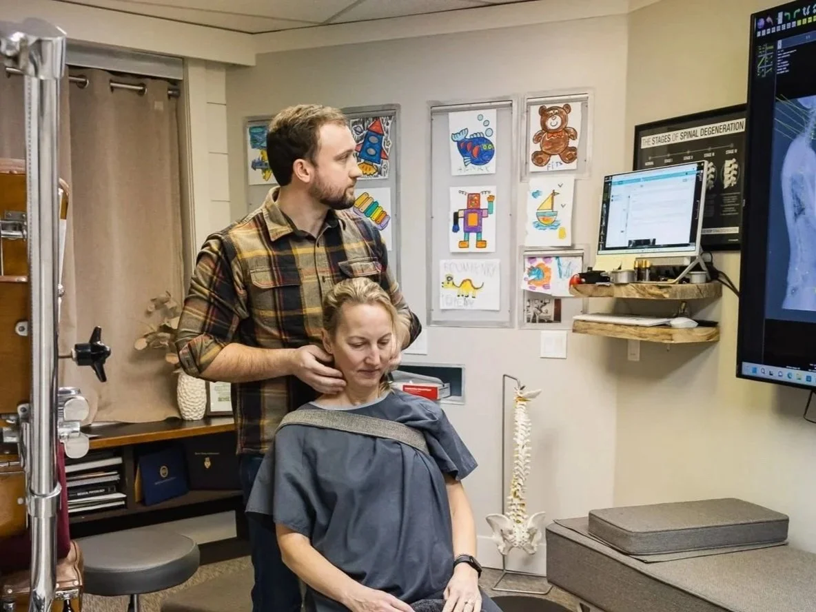 Dr. Peter Fennelly is inside his office Two Sparrows Family Chiropractic in Whitefish, Montana, checking the motion of a patients cervical spine while looking at a digital x-ray.