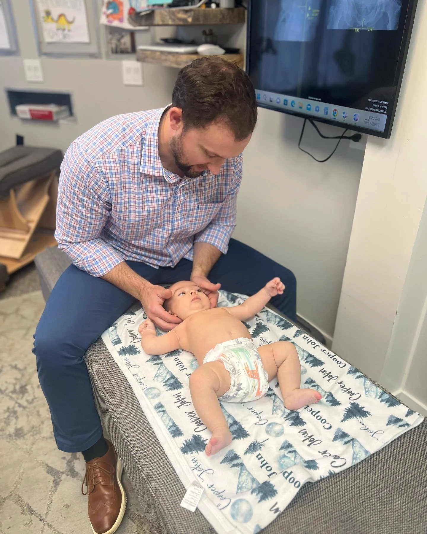 Dr. Peter of Two Sparrows Chiropractic in Whitefish, MT, providing a neck adjustment to a newborn boy