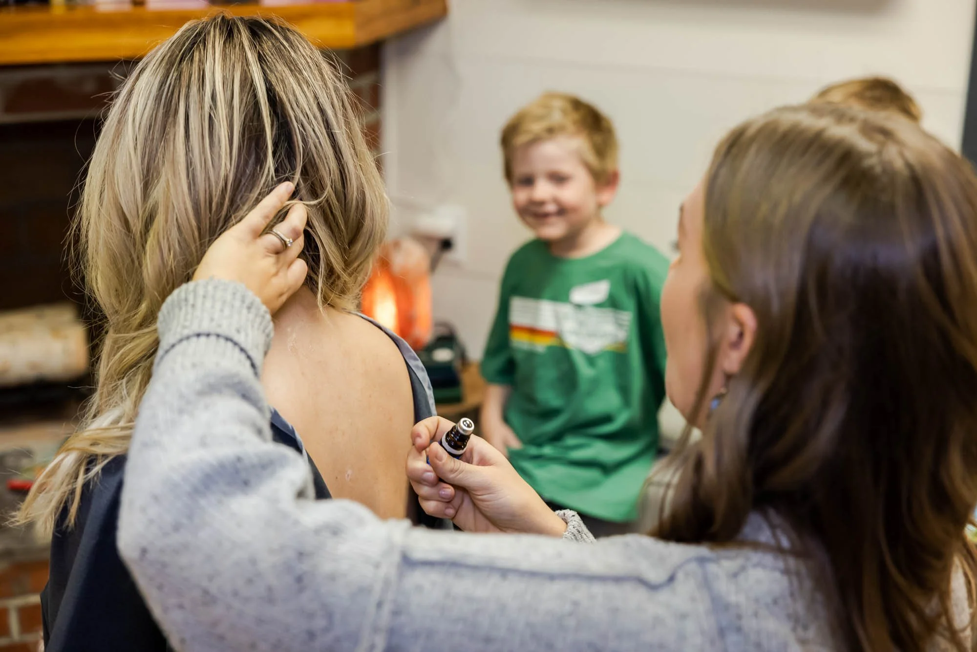A female patient is being assessed by Dr. Jordan Fennelly of Two Sparrows Family Chiropractic while her son is smiling in the background