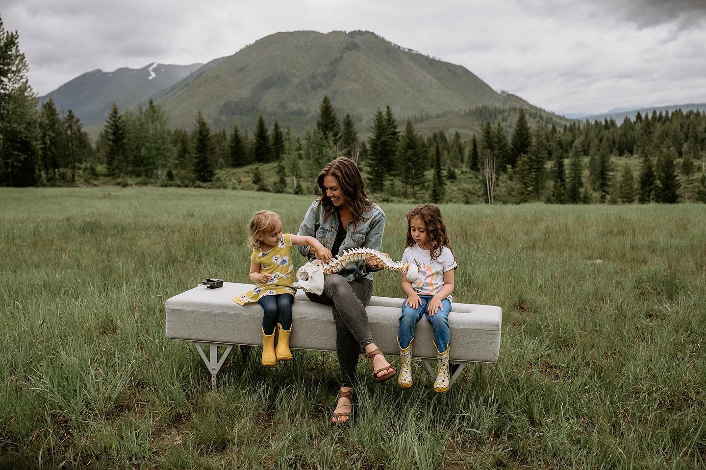 A woman and two young girls sitting and learning about the spine and the nervous system, outside of chiropractic office Two Sparrows Family Chiropractic in Whitefish, Montana