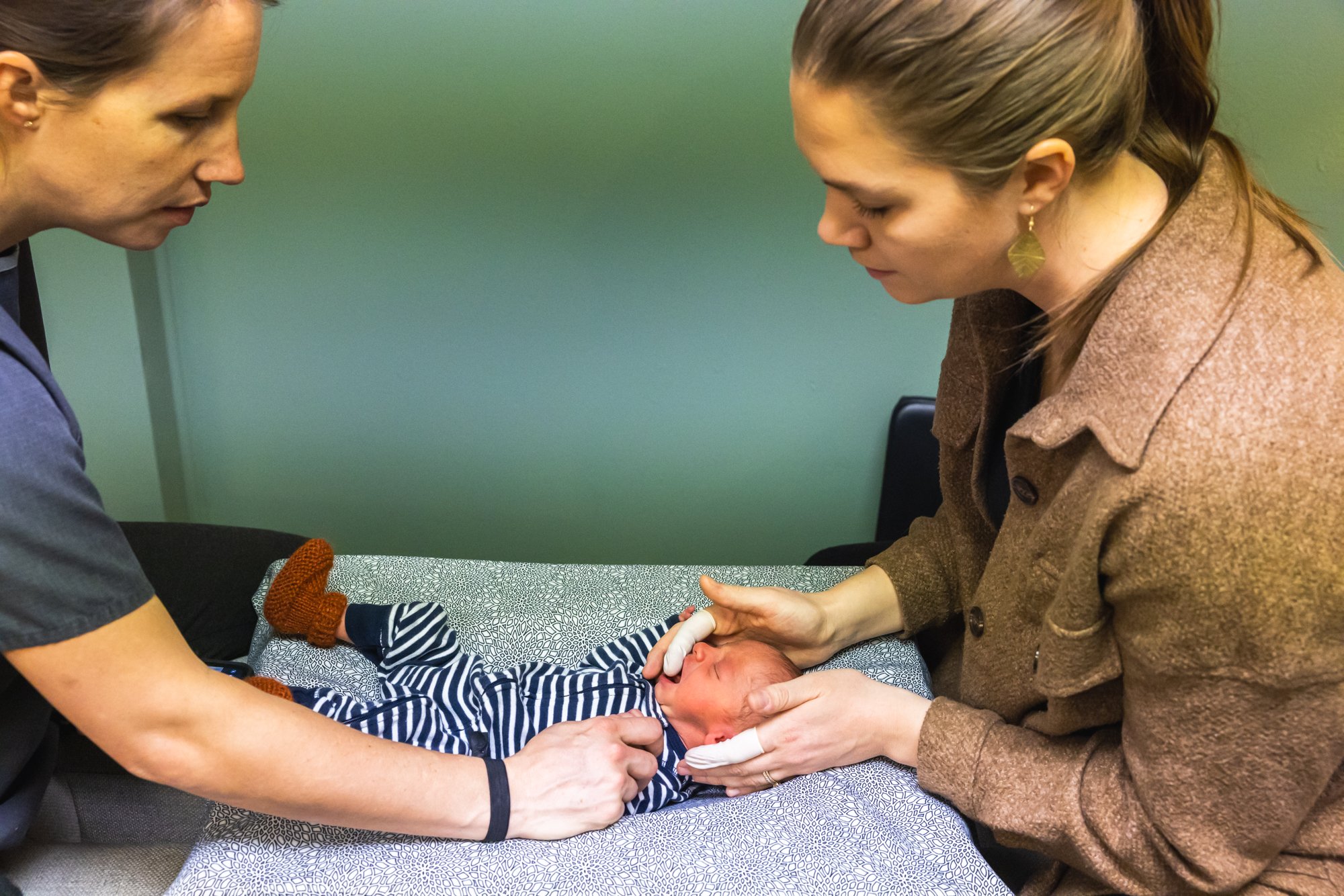 dr. jordan fennelly gently assessing newborn patient with her chiropractic exam