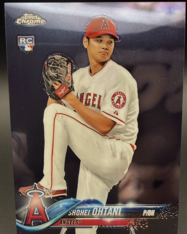 Sports trading card of Shohei Ohtani in a Los Angeles Angels uniform, kneeling with a baseball glove, wearing a red cap, with logos and text including 'Topps Chrome,' 'RC,' and his team details.