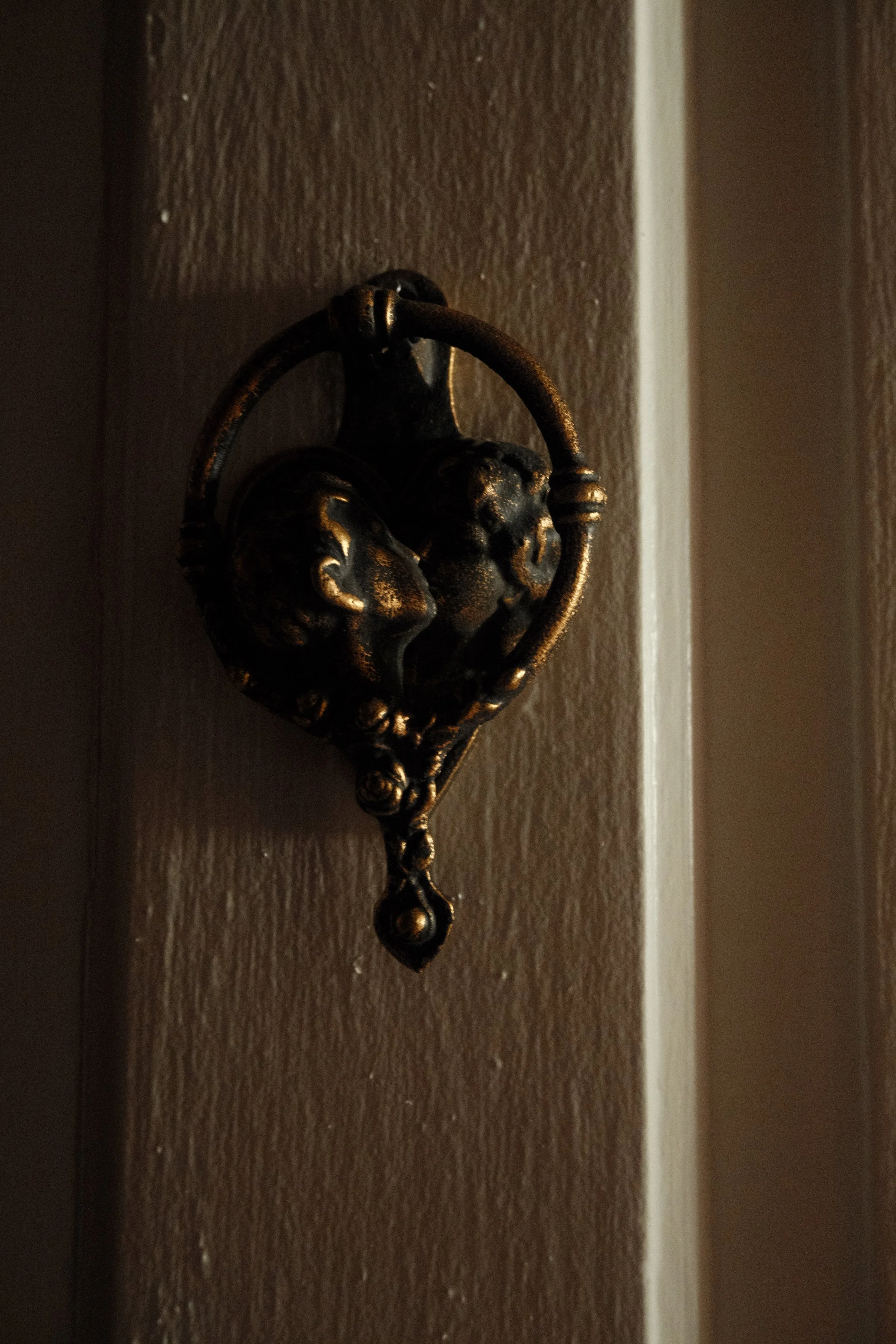 A vintage black and gold wall hook with ornate detailing, mounted on a brown wall.