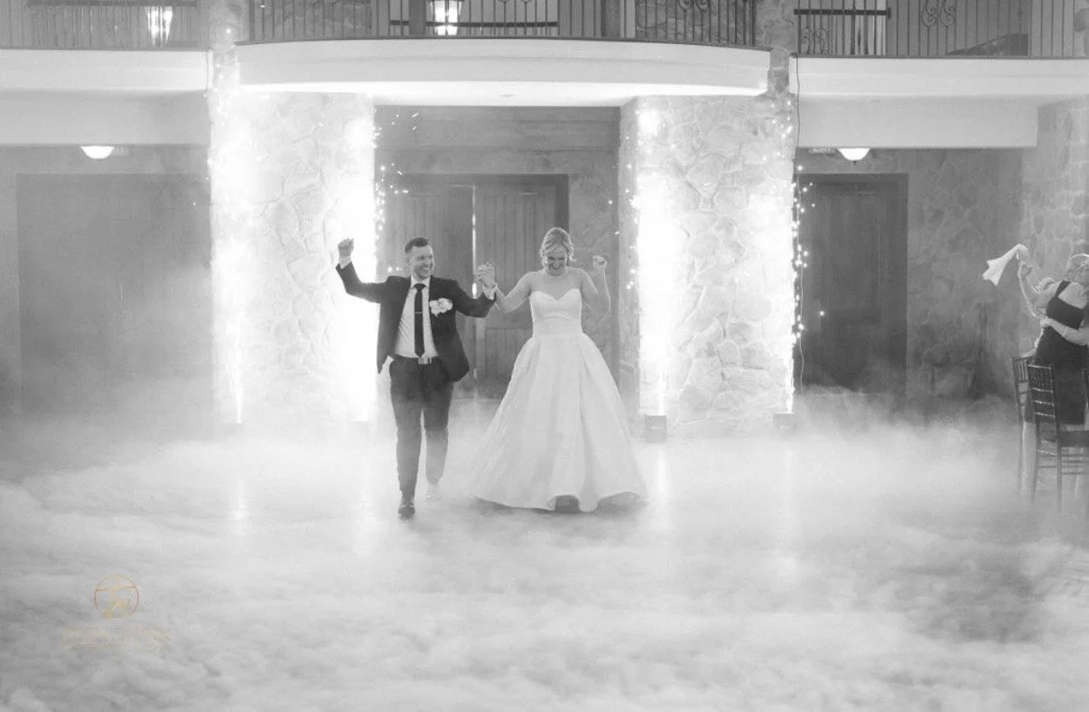 Black-and-white wedding entrance with cold spark fountains and low-lying fog.