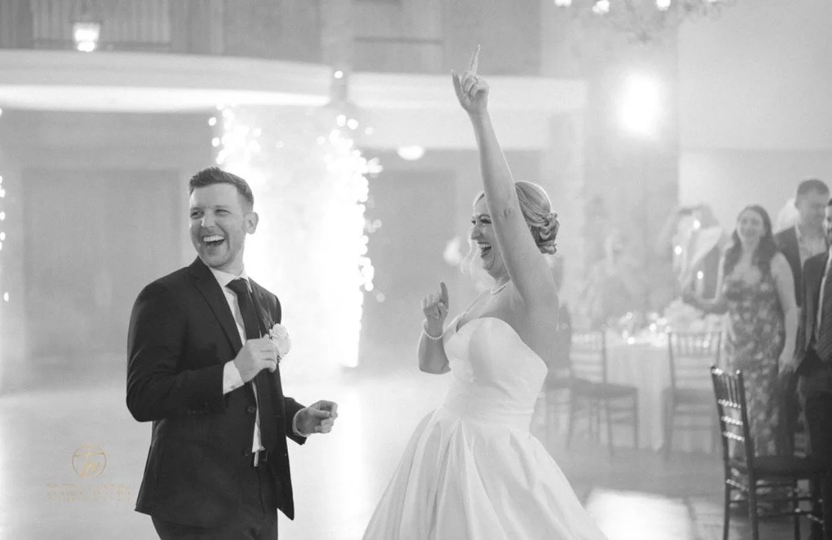 Bride and groom celebrate beside cold spark fountains.