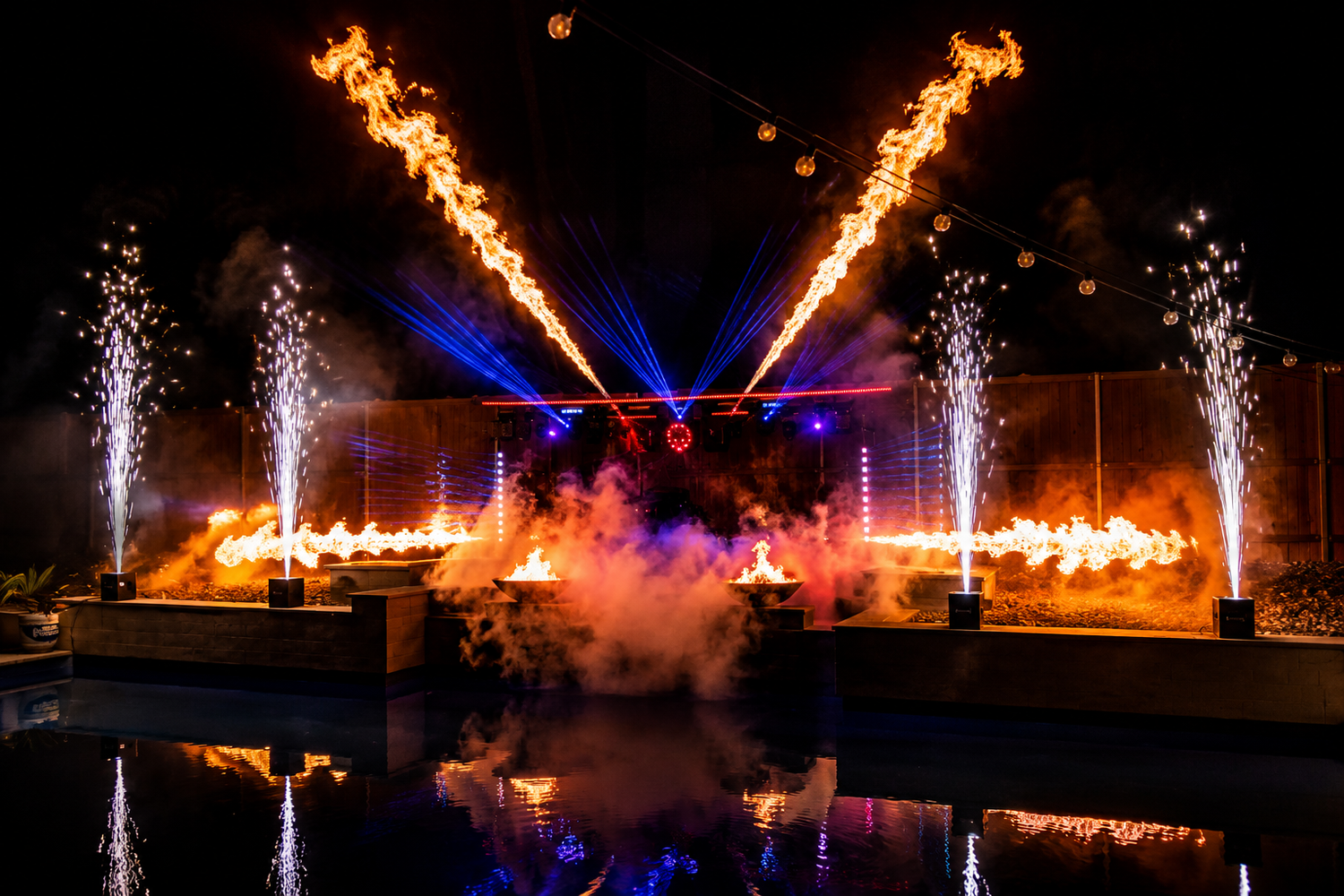 V-shaped flame jets, spark fountains and blue laser beams above a pool with low fog.