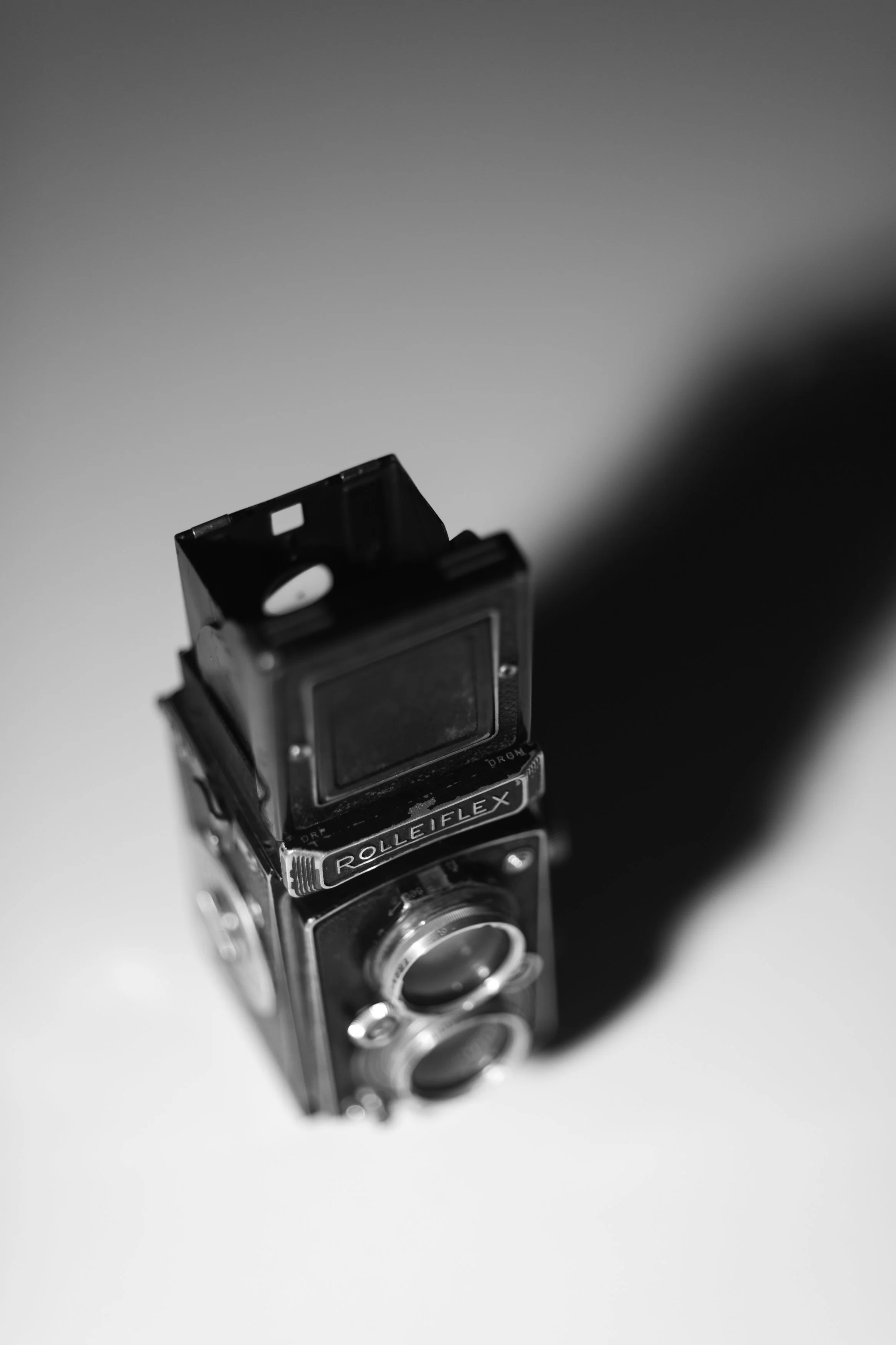 Black and silver vintage Rolleiflex twin-lens reflex camera, top view, on a light background.