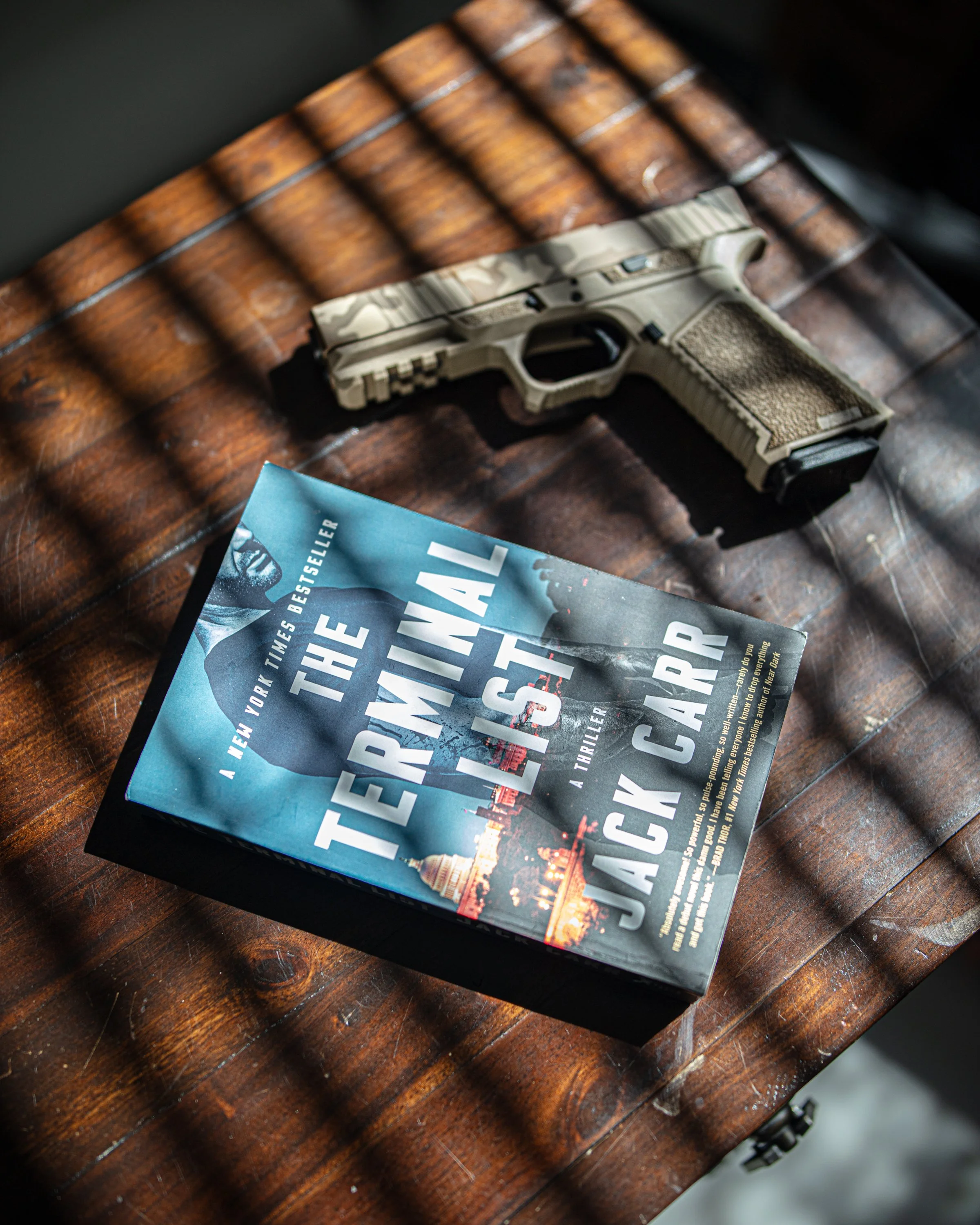 A gun resting on a wooden surface next to a book titled 'The Wall Street Journal' with a cityscape background on the cover.