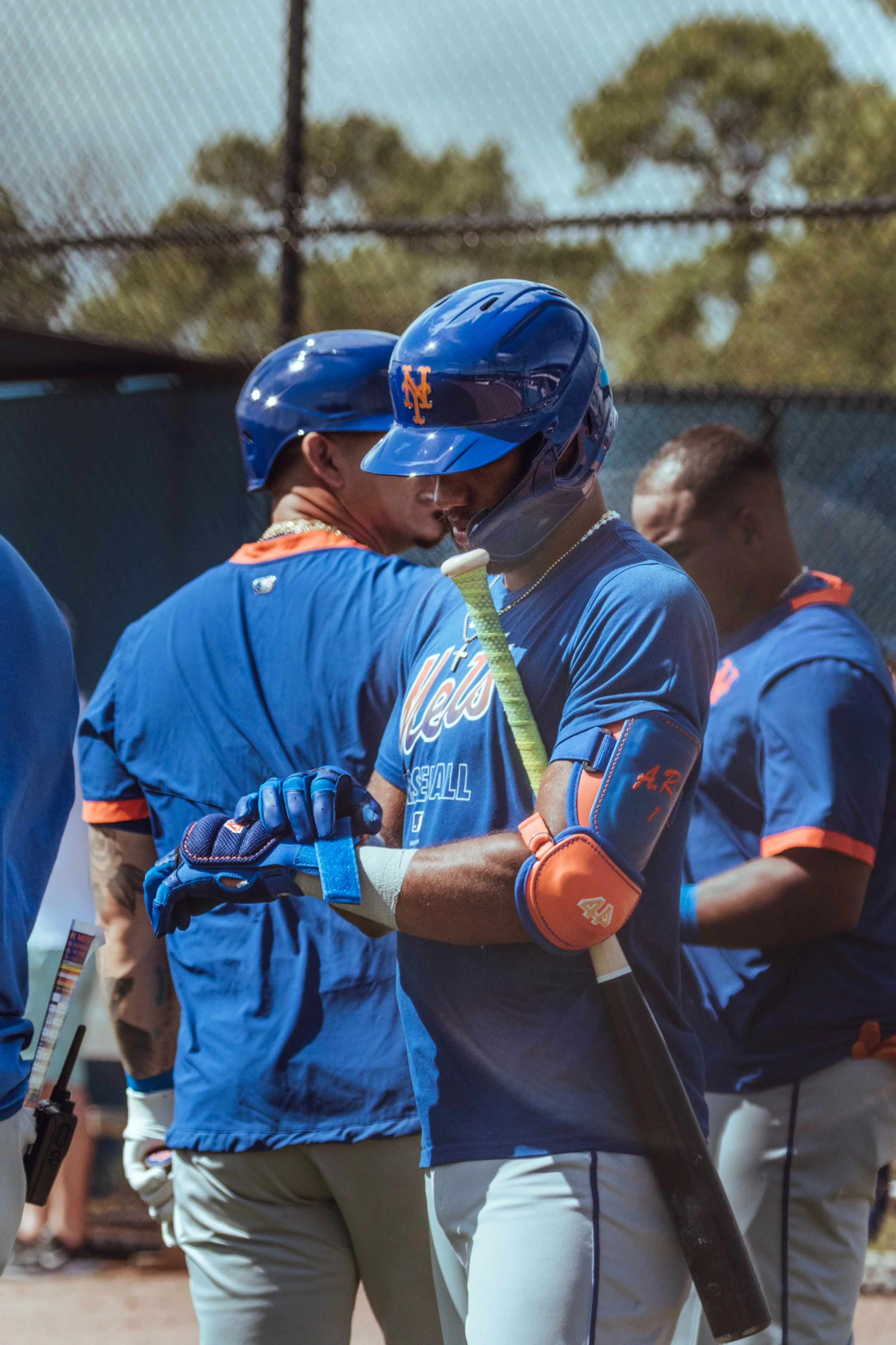 Two baseball players wearing blue uniforms and helmets engaging in a moment of celebration or support on the field.