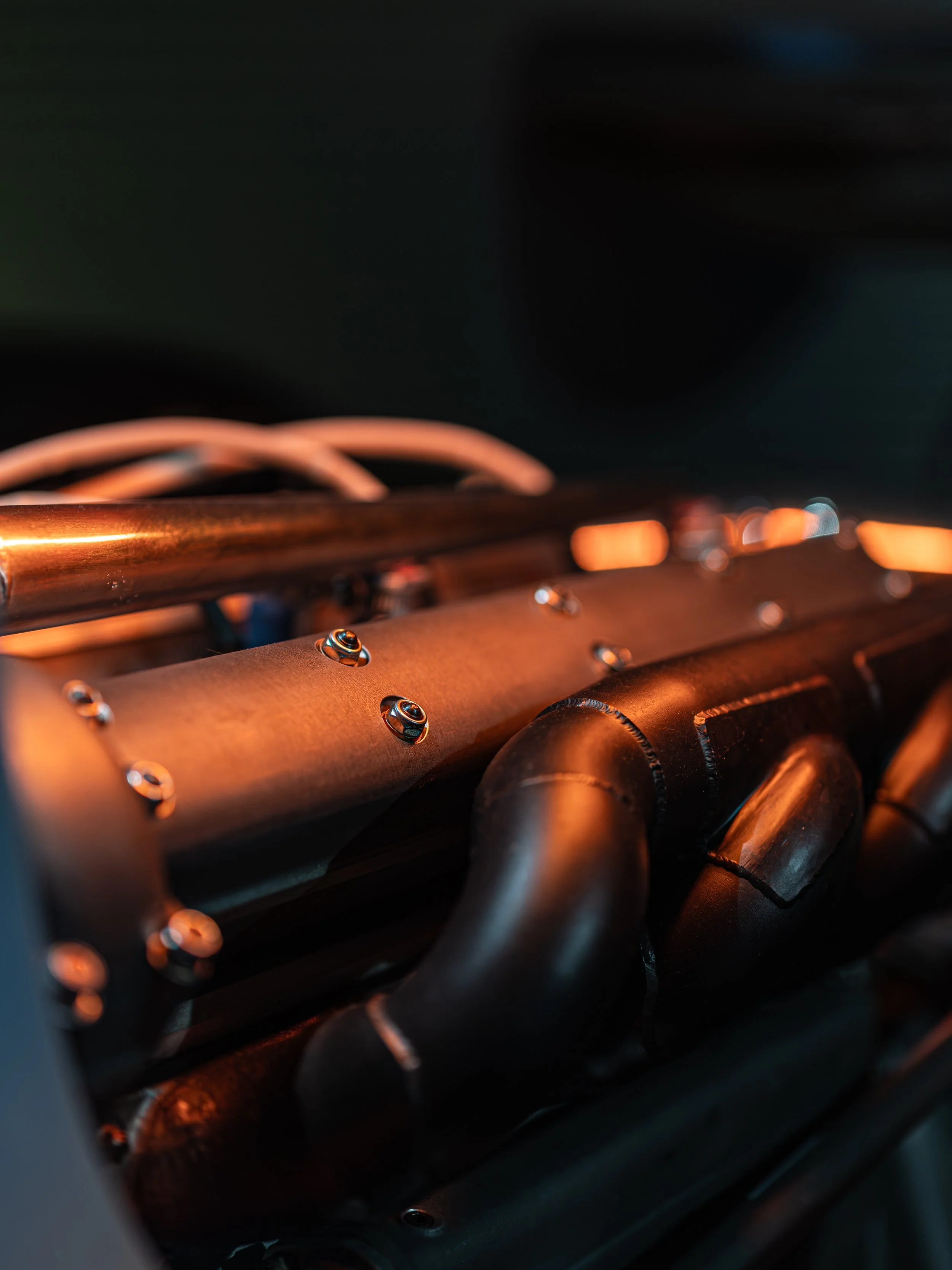 Close-up of a metallic grill with shiny screws, likely part of a machine or electronic device, with a dark background.