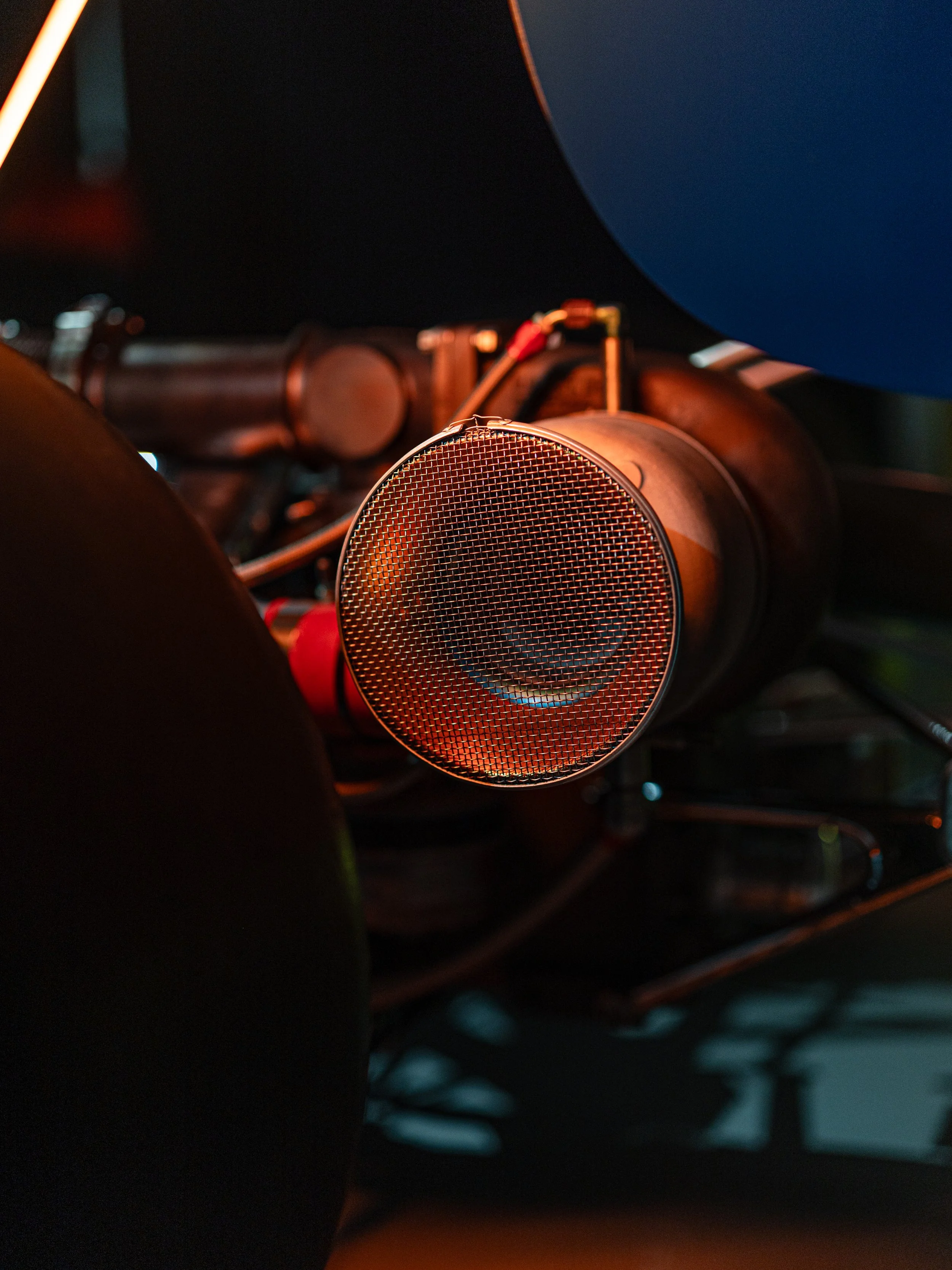 Close-up of a car's interior, showing the dashboard with a focus on a microphone or speaker and some wiring, with the steering wheel partially visible.