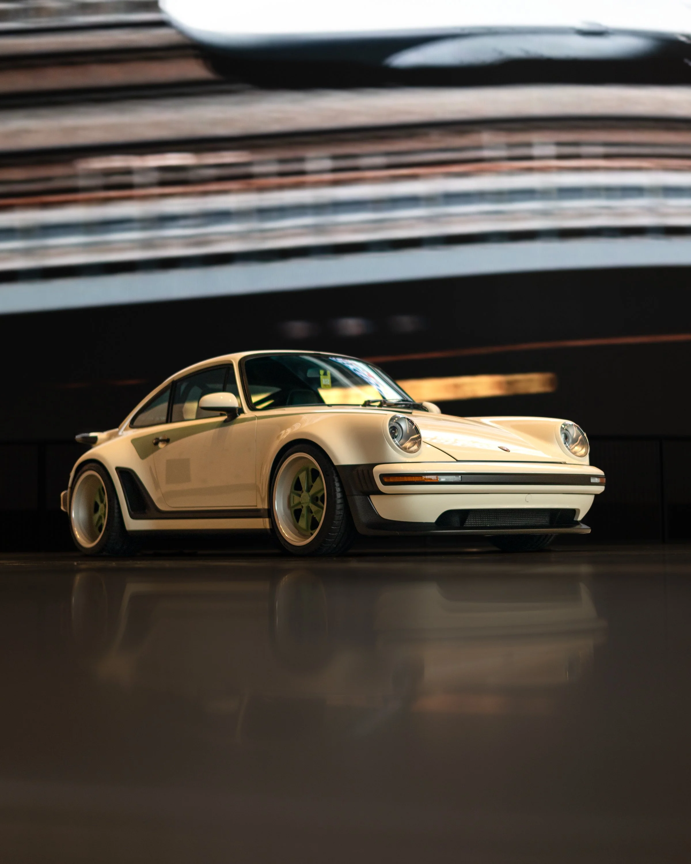 White vintage Porsche 911 sports car displayed on a reflective floor