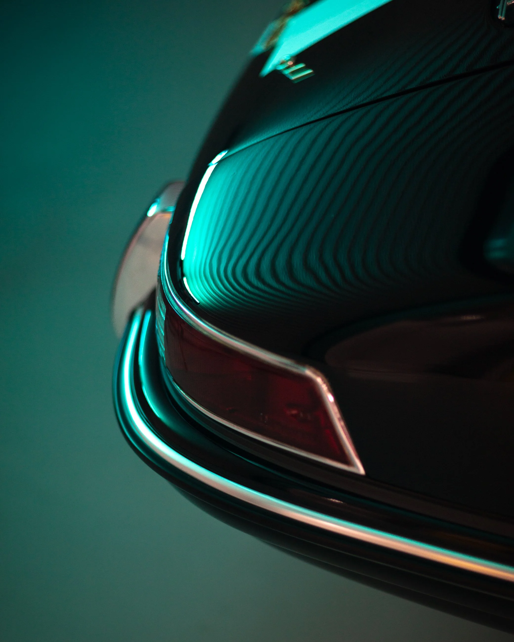 Close-up of a metallic car wheel with glowing teal accents on a dark background. Porsche 911.