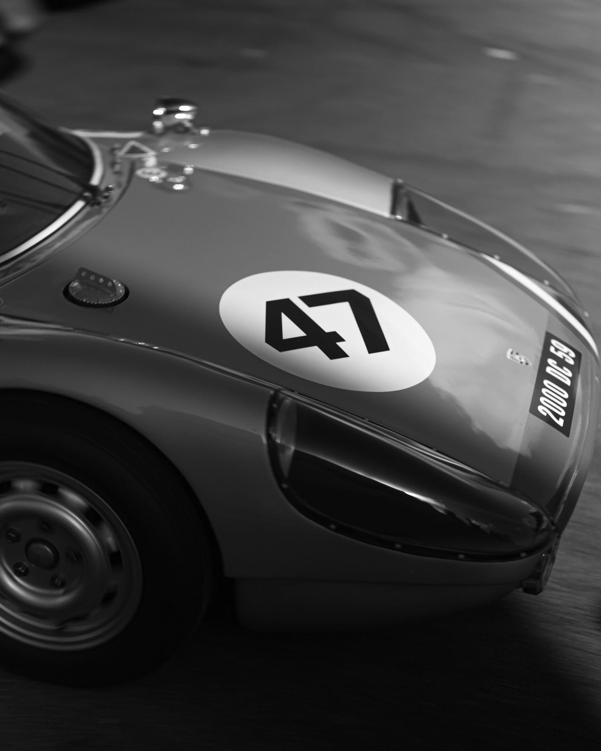 Close-up of a vintage race car's front section, showing an aerodynamic design, a large racing number 41 on the hood, and a blurred background indicating high speed.