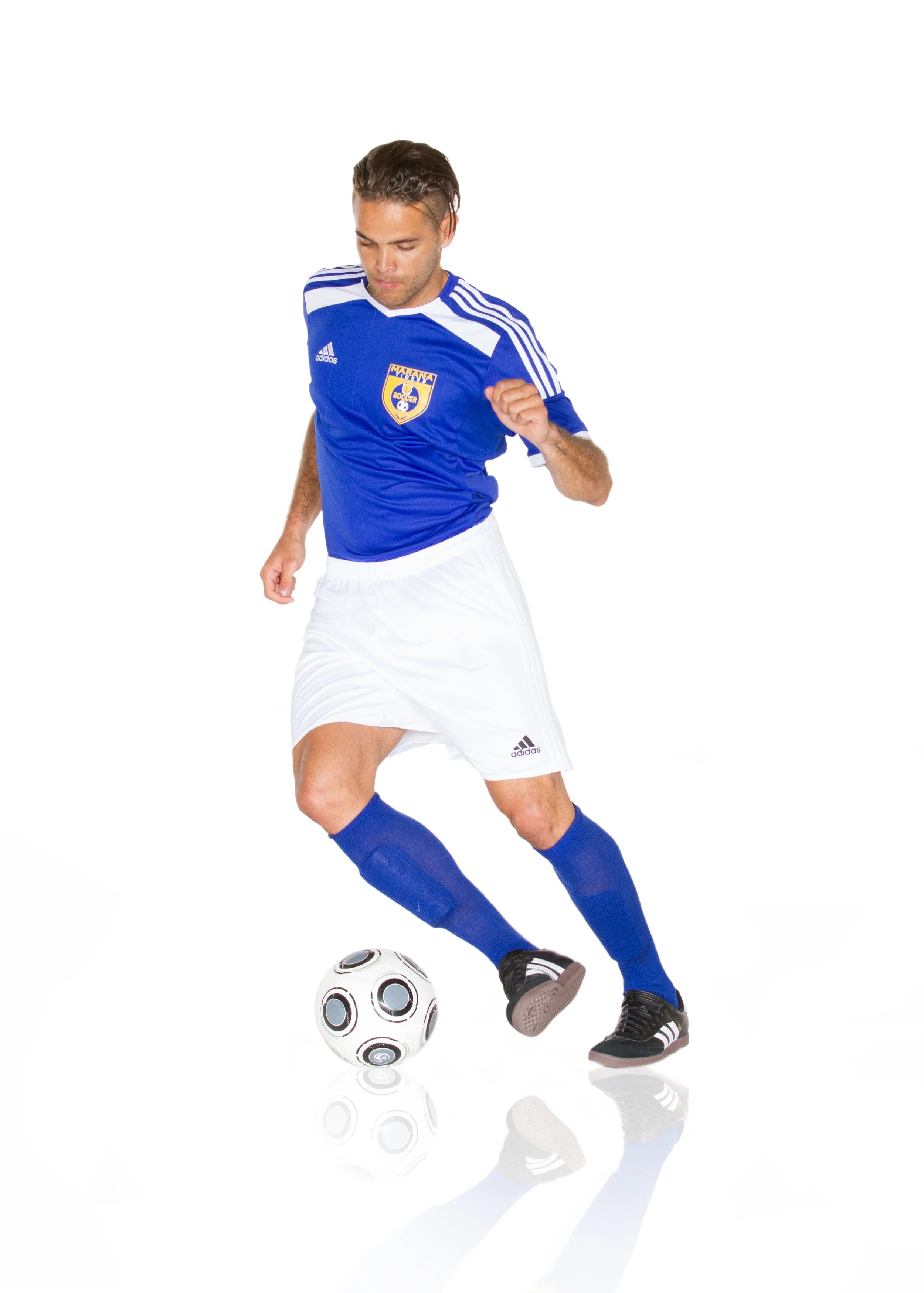 A male soccer player in a blue and white uniform kicking a soccer ball