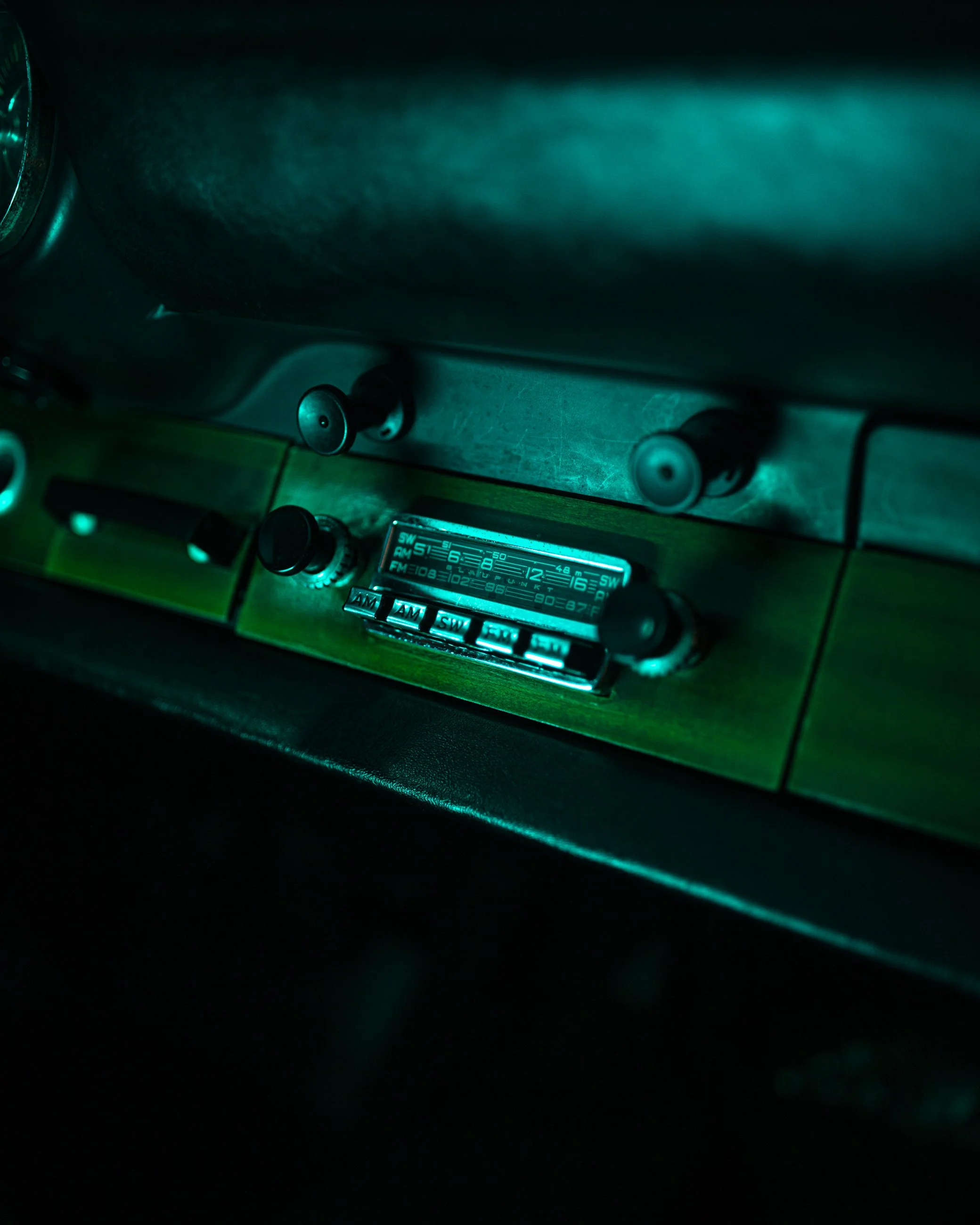 Close-up of a vintage car dashboard with illuminated radio controls and green backlit display.