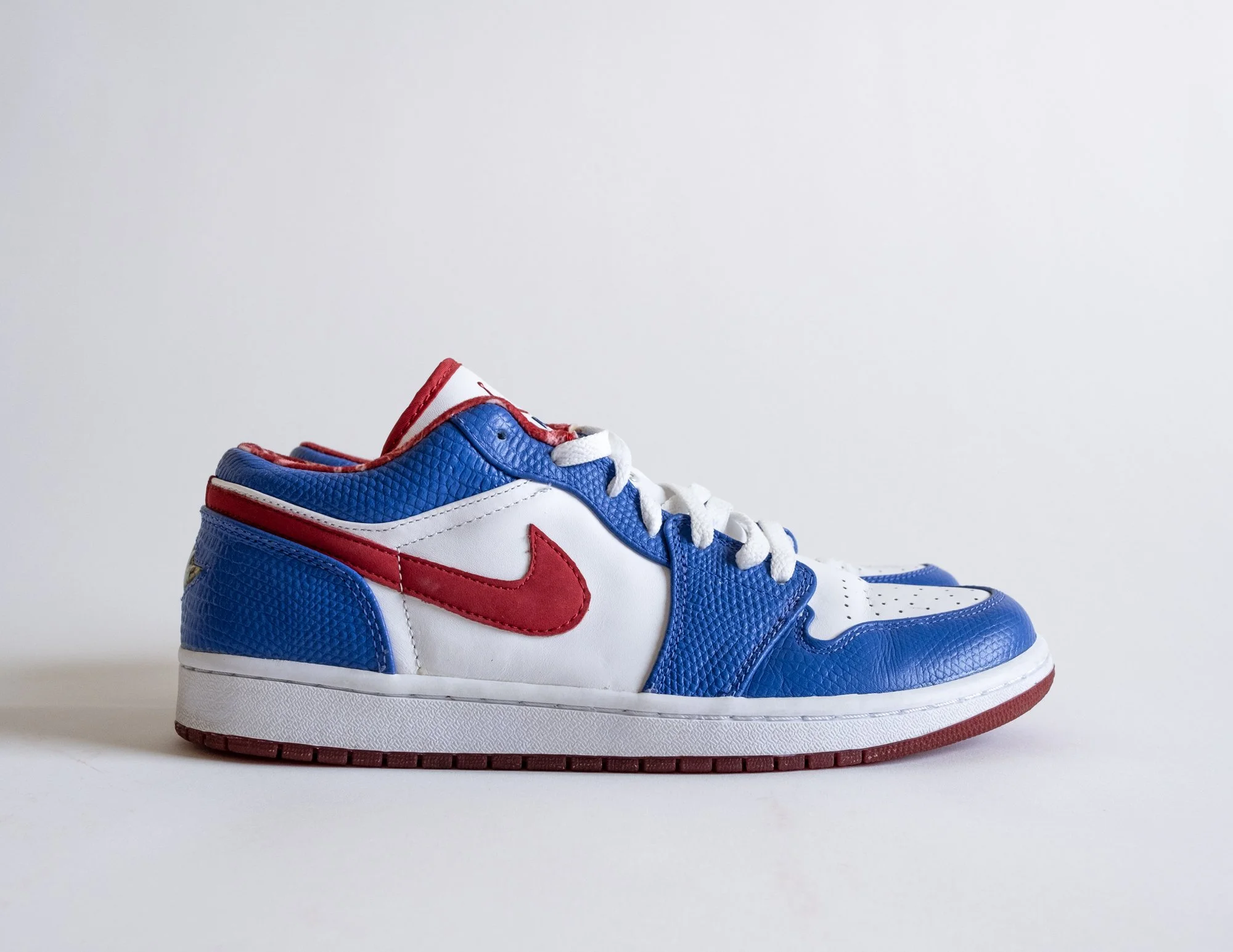 A colorful sneaker with blue, red, and white accents displayed against a plain white background. Nike.