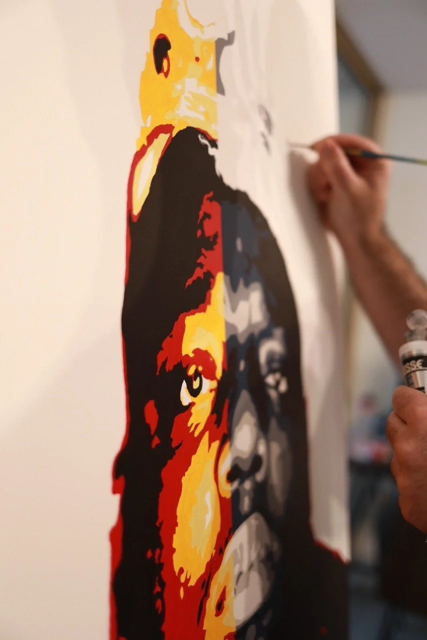 Person painting a colorful portrait of a face on a canvas.