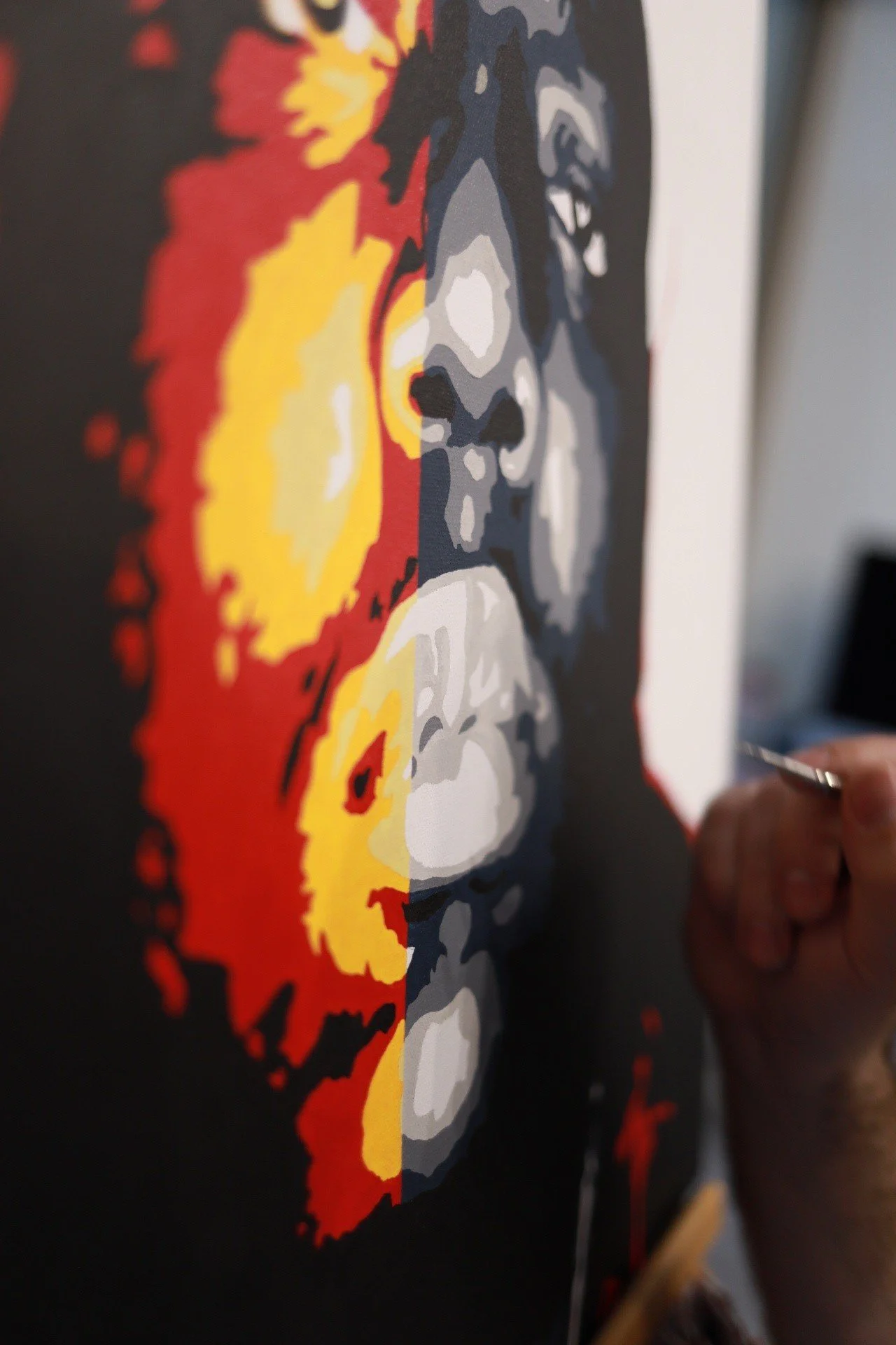 Close-up of a person painting a stylized portrait of a woman with colorful and bold brushstrokes on a black canvas.