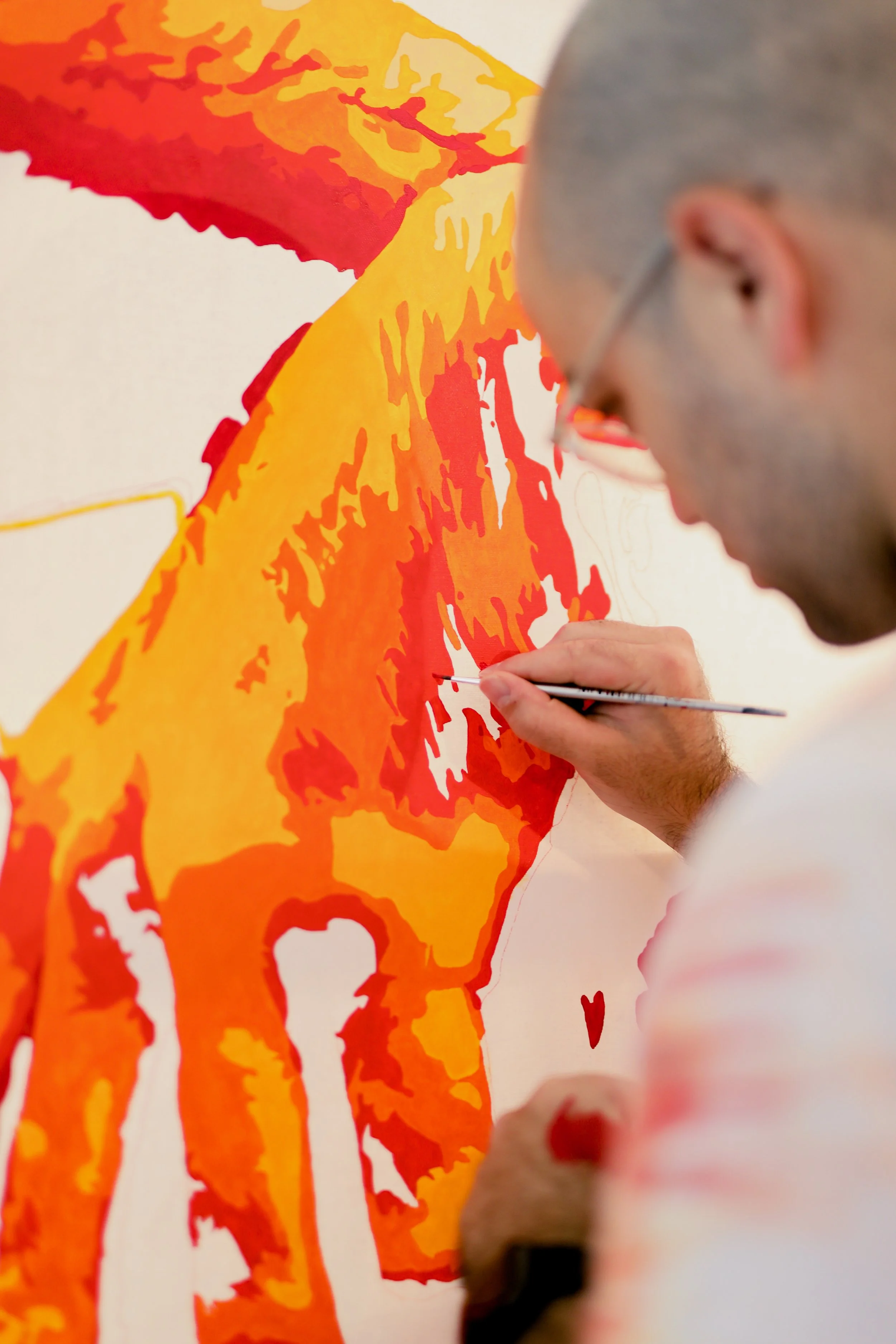 A man painting a colorful abstract image of a bear on a white canvas.