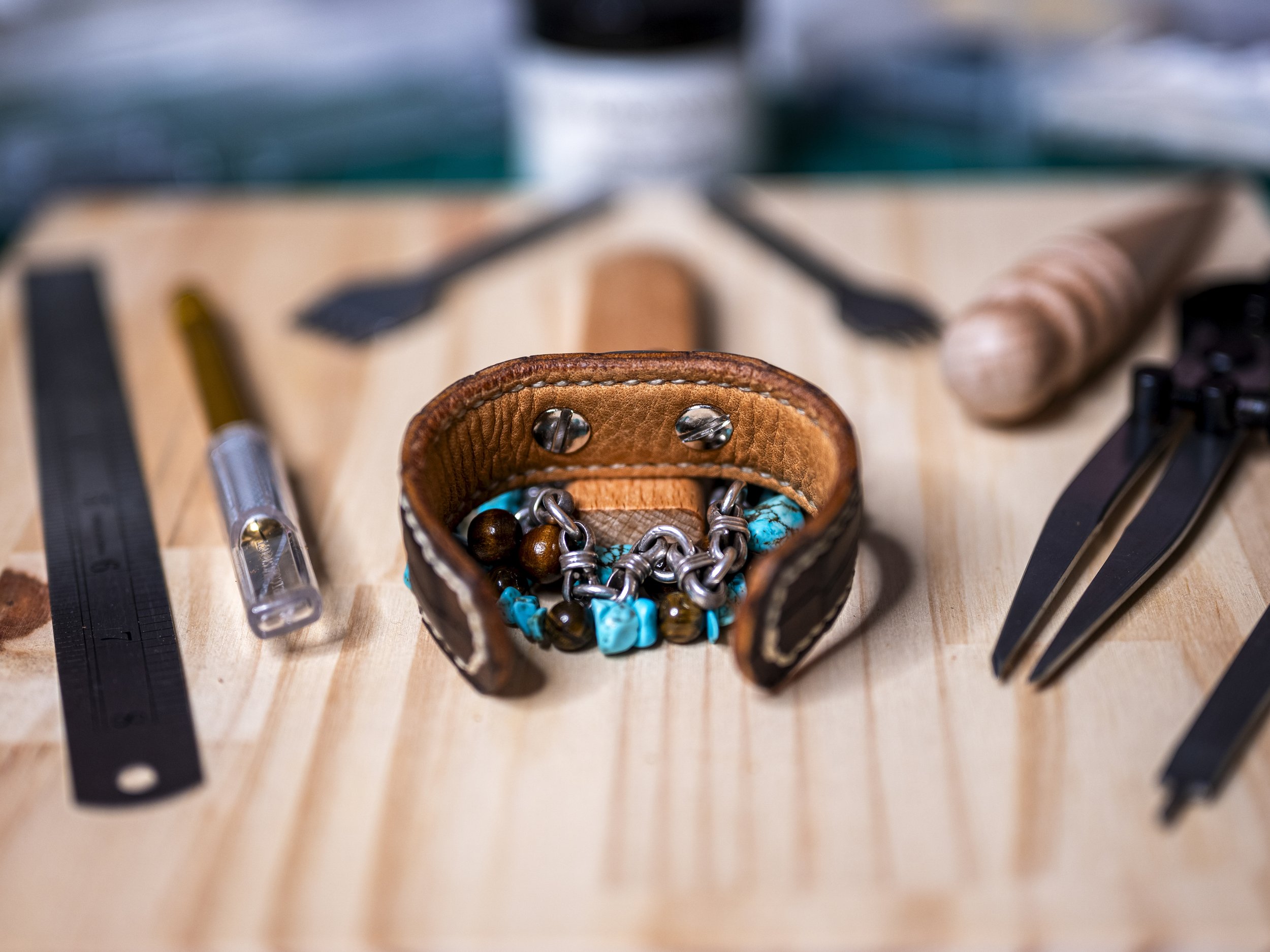 Close-up of a small leather pouch filled with assorted jewelry, on a wooden surface with black measurement markings.