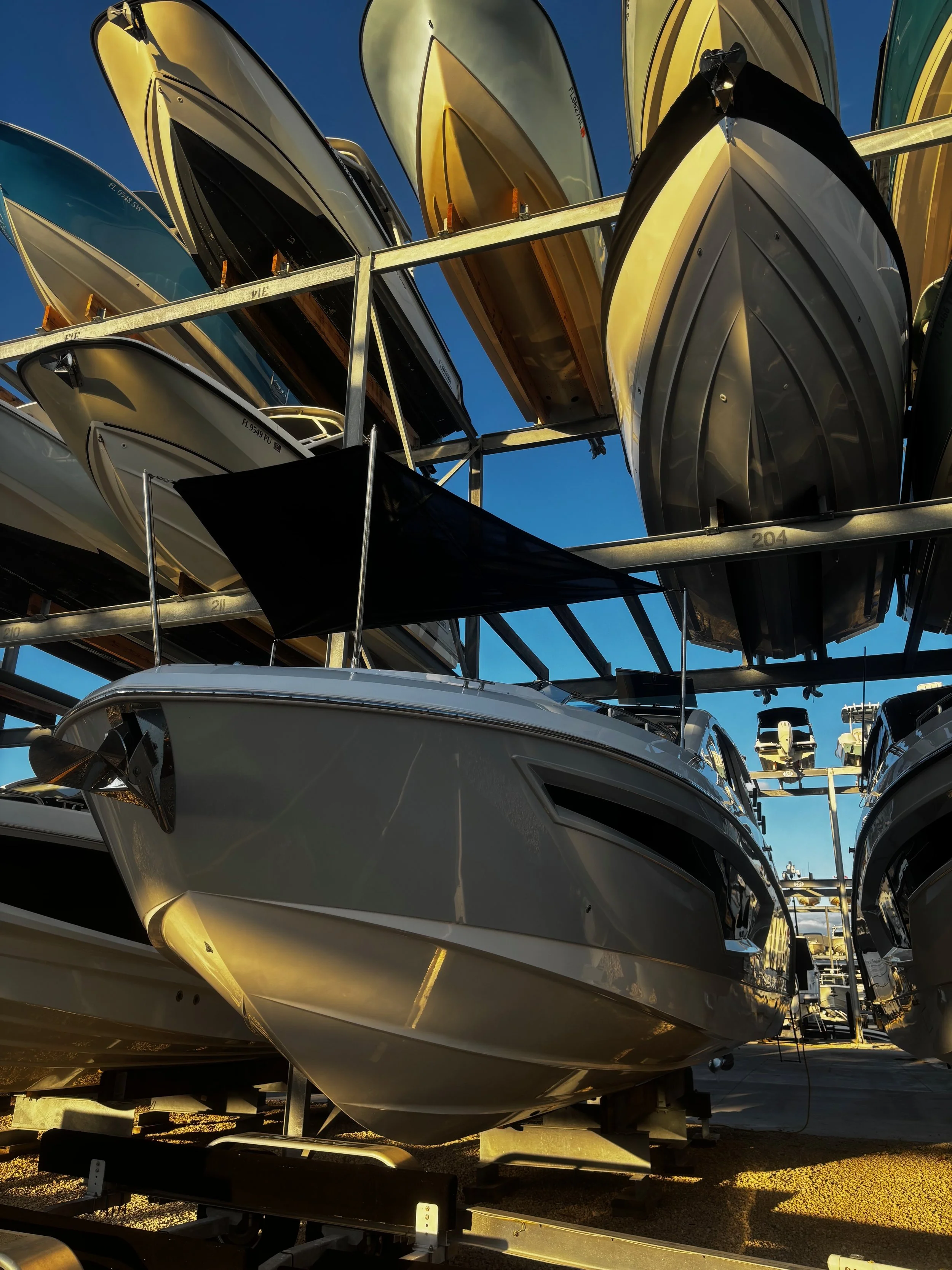 A boat with a custom deck cover stored on a multi-level boat rack with a clear blue sky in the background.