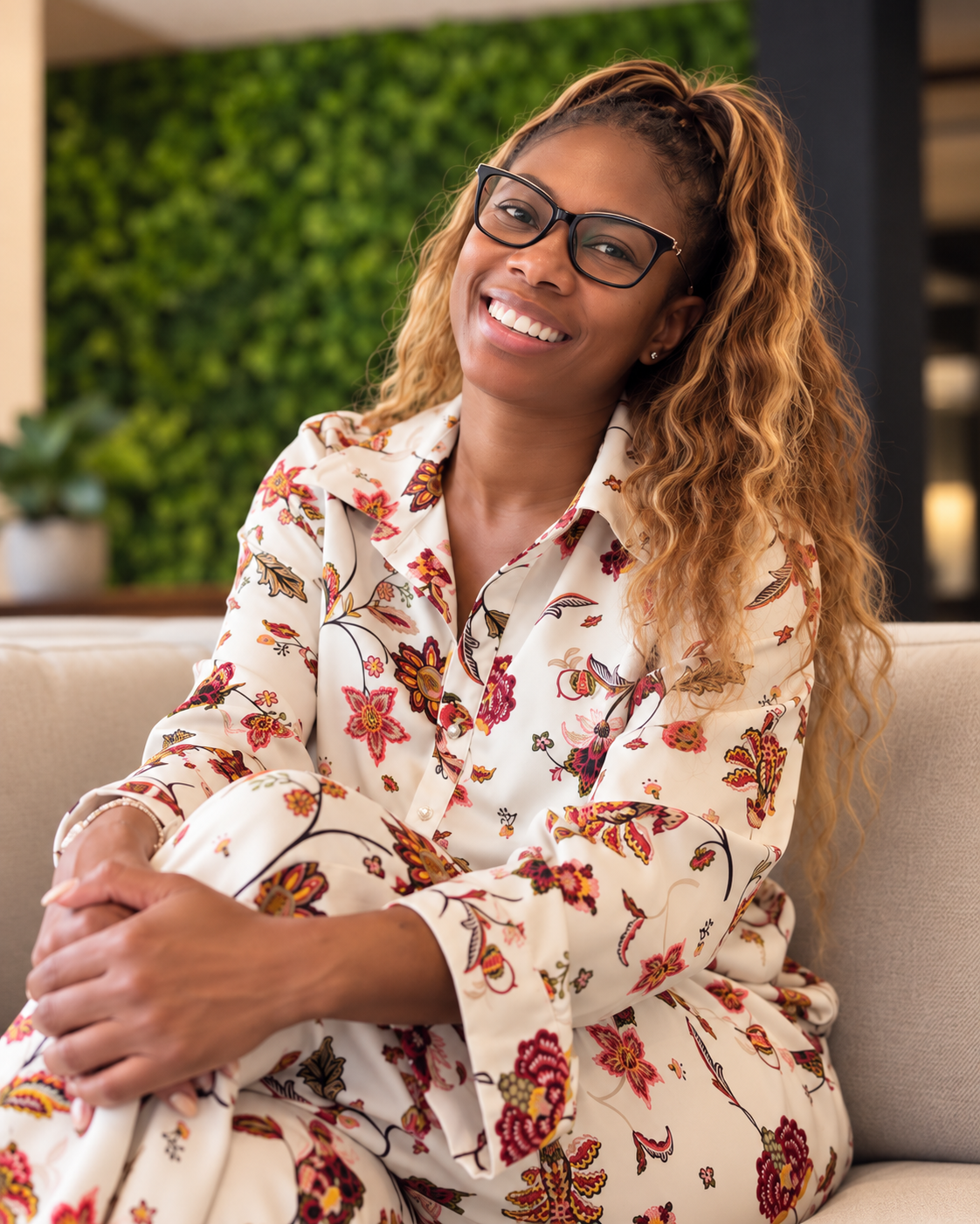 Erica Ward, MPH, LCSW-QS, seated on a sofa in a floral outfit.