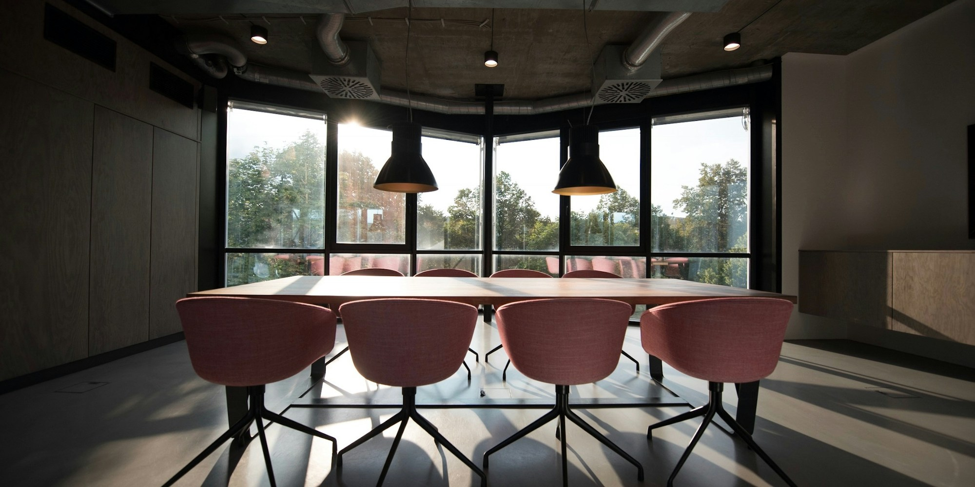 Modern conference room with pink chairs around a wooden table