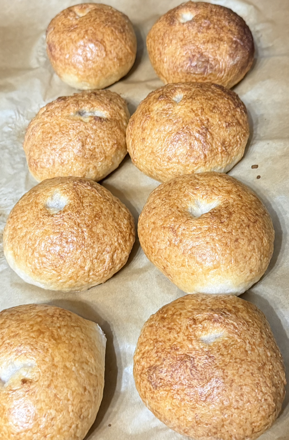 Six freshly baked, golden brown bread rolls on parchment paper.