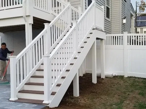 White outdoor staircase with handrails leading to a second-story deck in a backyard