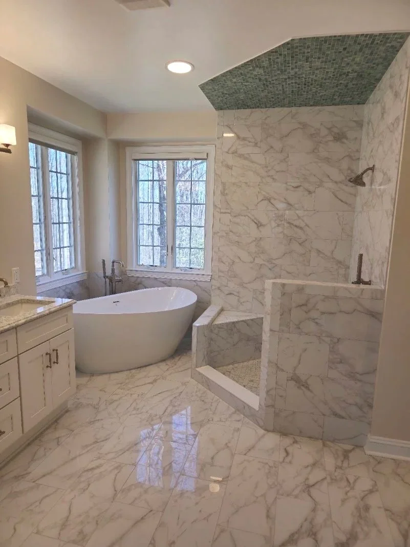Bathroom with marble floors, and walls, a freestanding bathtub by windows, a walk-in shower with marble tiles, and a green mosaic ceiling in the shower area.