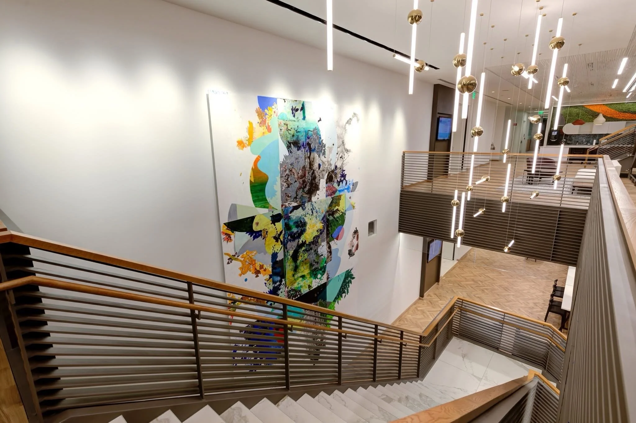 Modern interior of a building with wooden stairs, railing, and bright hanging lights, featuring a colorful abstract mural on the wall.