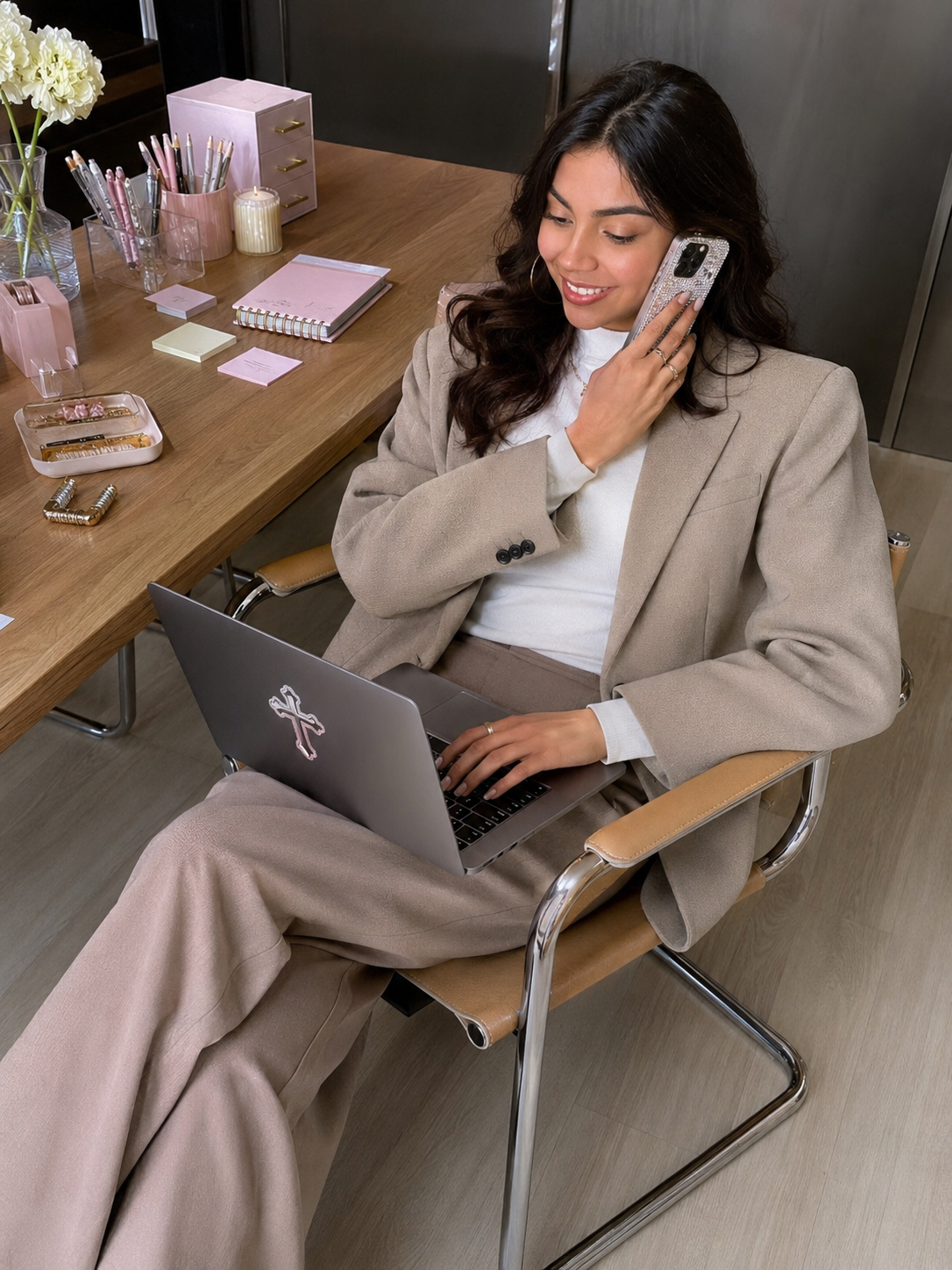 Rebecca, founder of Rebecca's Boutique, on a phone call at her desk with a rhinestone cross sticker on her laptop