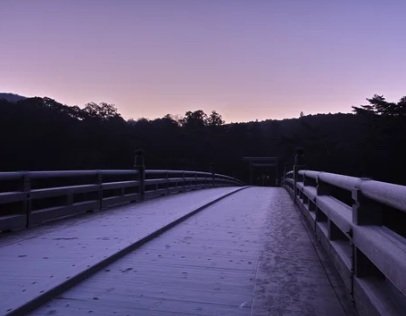 雪に覆われた橋と鉄道路線路の風景。夕暮れ時の空が紫色に染まっている。