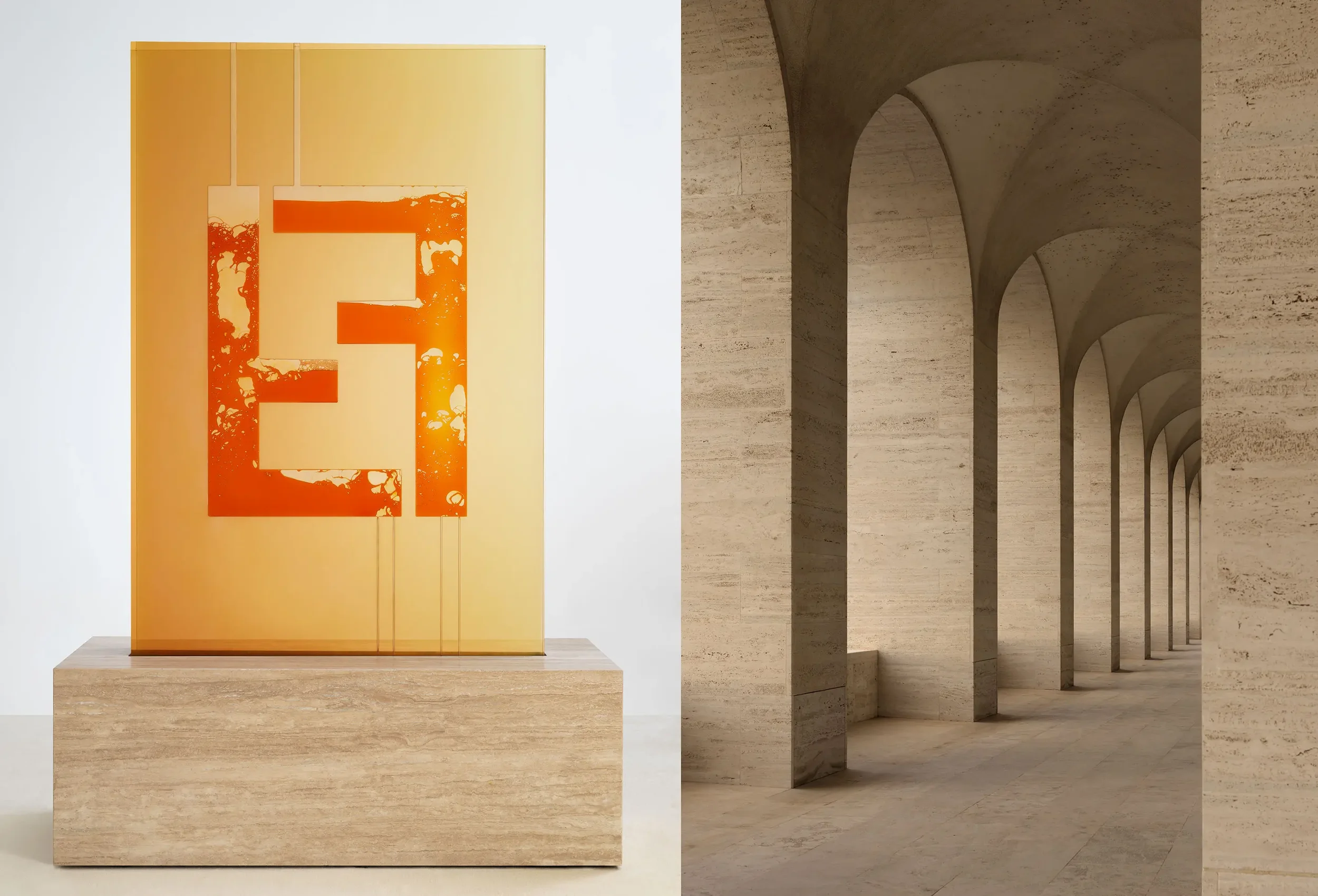 An orange and yellow abstract artwork on a yellow wall with vertical panels, situated on a beige stone pedestal in a gallery setting, next to a corridor with arched openings and beige stone walls and floors.
