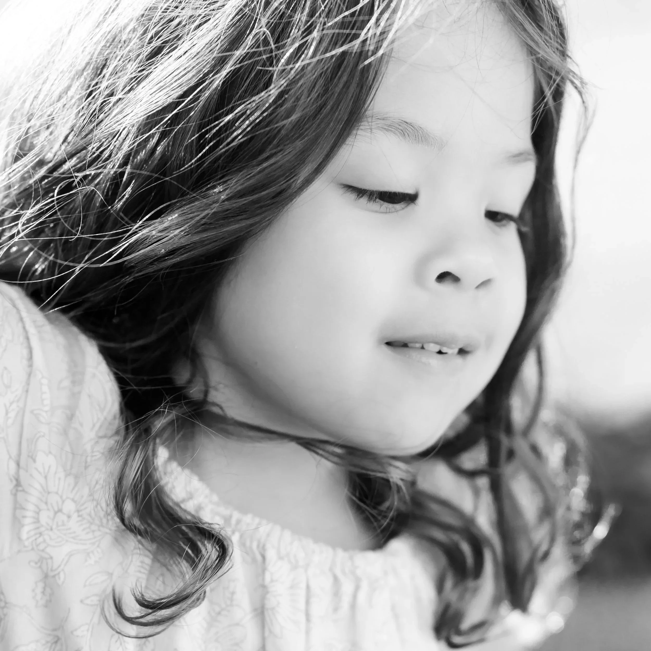 Close-up of a woman's face with wavy hair and closed eyes in black and white located in Glenview IL.