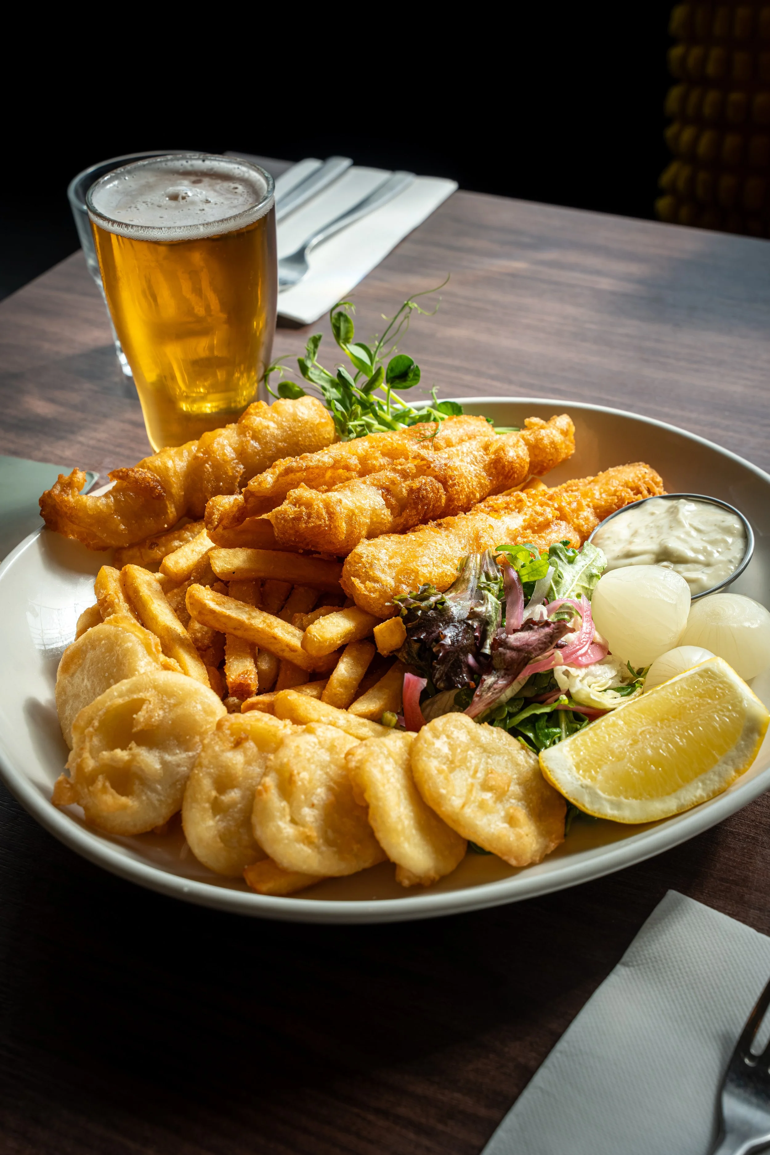 Photo of fish and chips, served with salad and a pint of beer