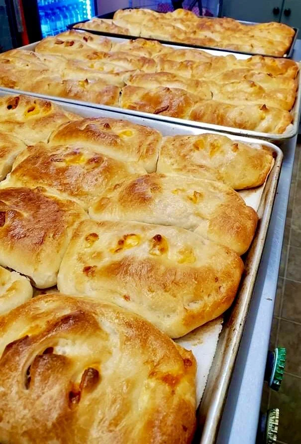 Freshly baked cheesy stuffed bread rolls on baking trays.