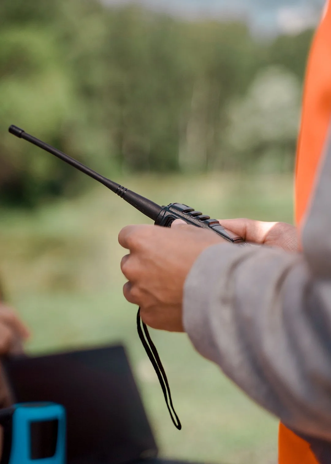 Person holding a radio communication device outdoors.